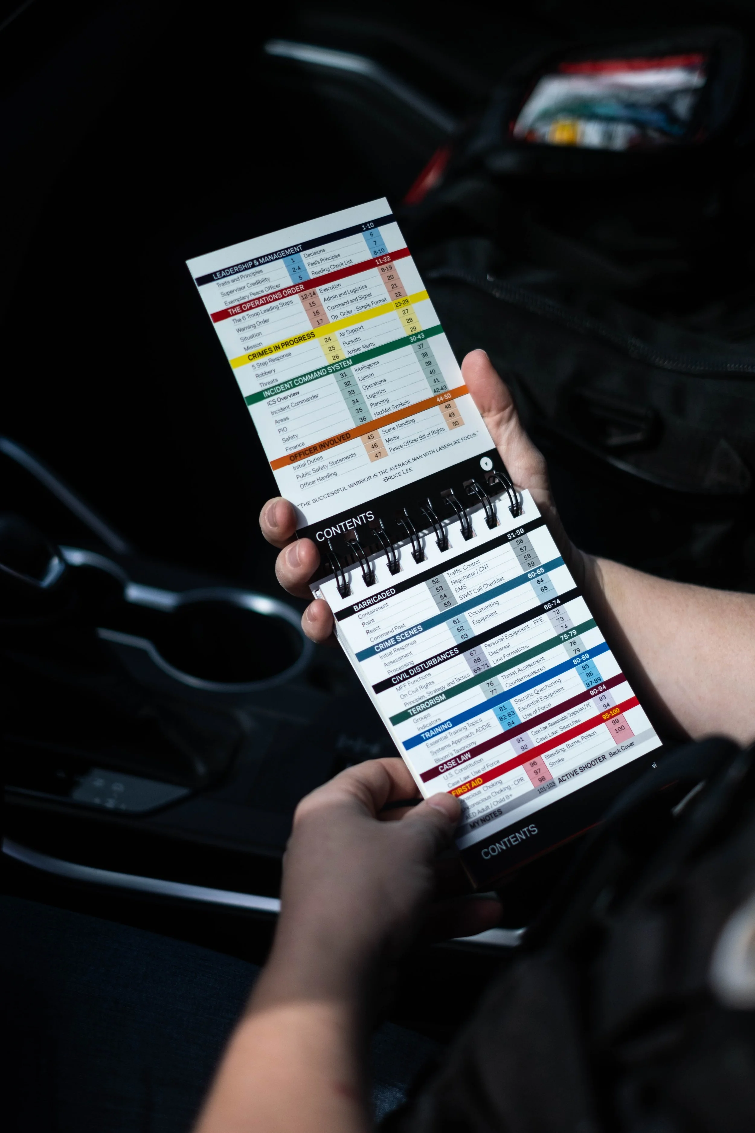 Person holding a mobile device displaying a digital booklet or playlist on a car's center console.