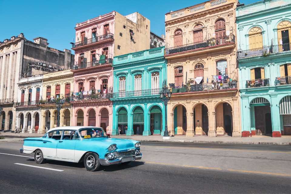 An oldsmobile in front of row houses in Cuba