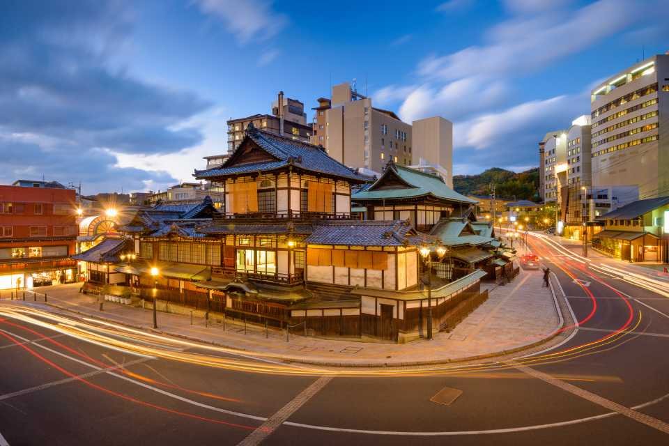 A traditional Japanese building sits next to modern buildings in Matsuyama, Japan