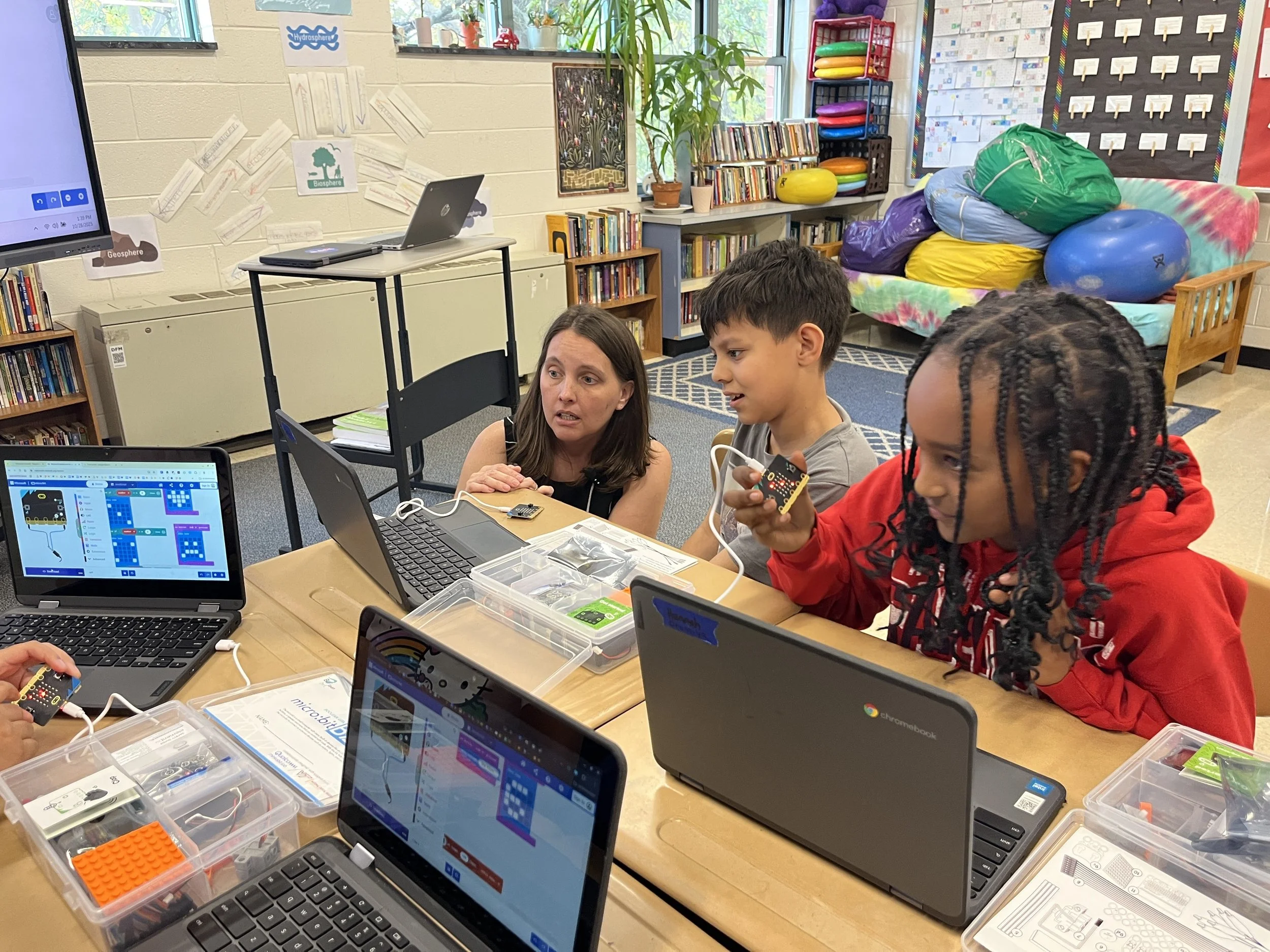 Kids at desk with teacher.JPG