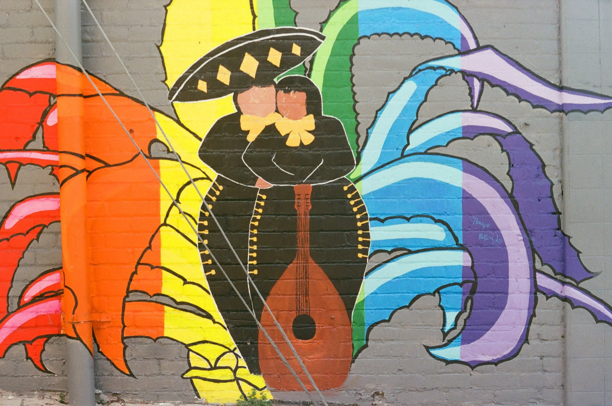 Colorful graffiti mural of butterflies with large, vibrant wings in orange, yellow, green, blue, purple, and black, painted on a brick wall.