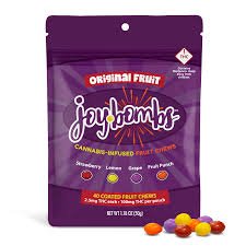 Purple bag of Joyful Bums Original Fruit candy with assorted fruit-flavored candies spilled in front.