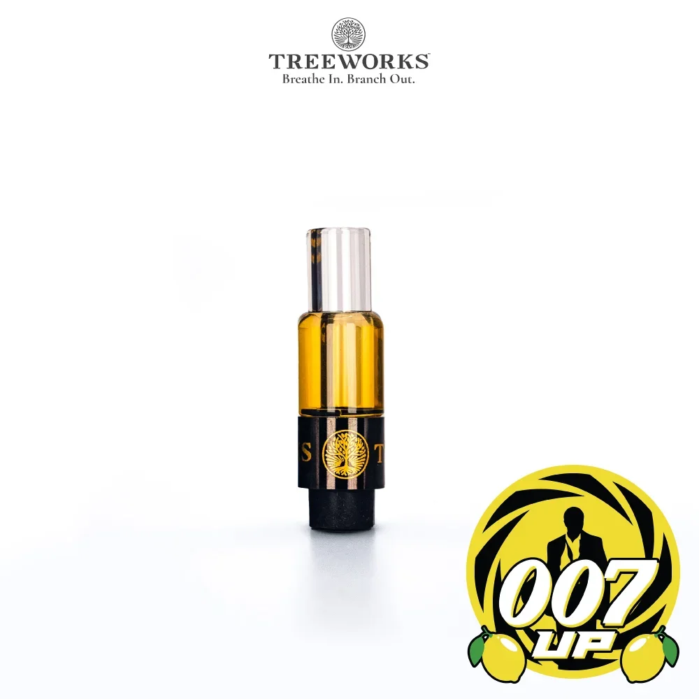 A small amber glass spray bottle with a silver cap and a black band around its middle, featuring a gold tree logo. The background is white, with a logo in the bottom right corner incorporating a silhouette of a man in a suit, the number '007', and lemon illustrations, with the text 'UP'.