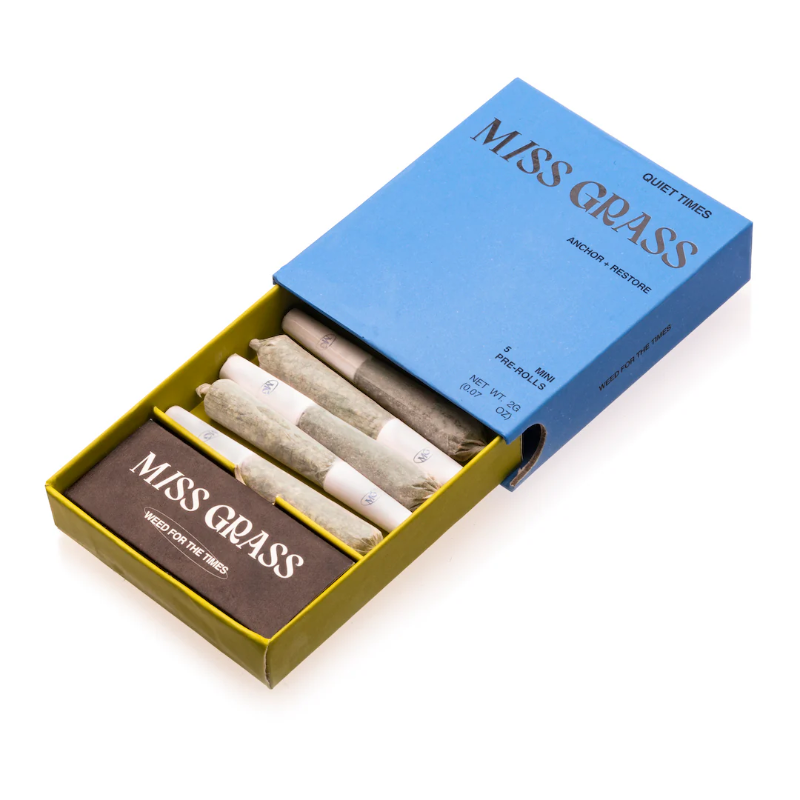 A box of Miss Grass pre-rolled mini joints with a blue lid and yellow base, partially open to show the pre-rolls and a brown packet inside.