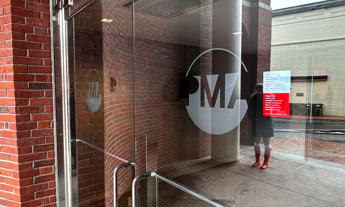 Glass entrance of Portland Museum of Art featuring institutional identity design applied to architectural environment.