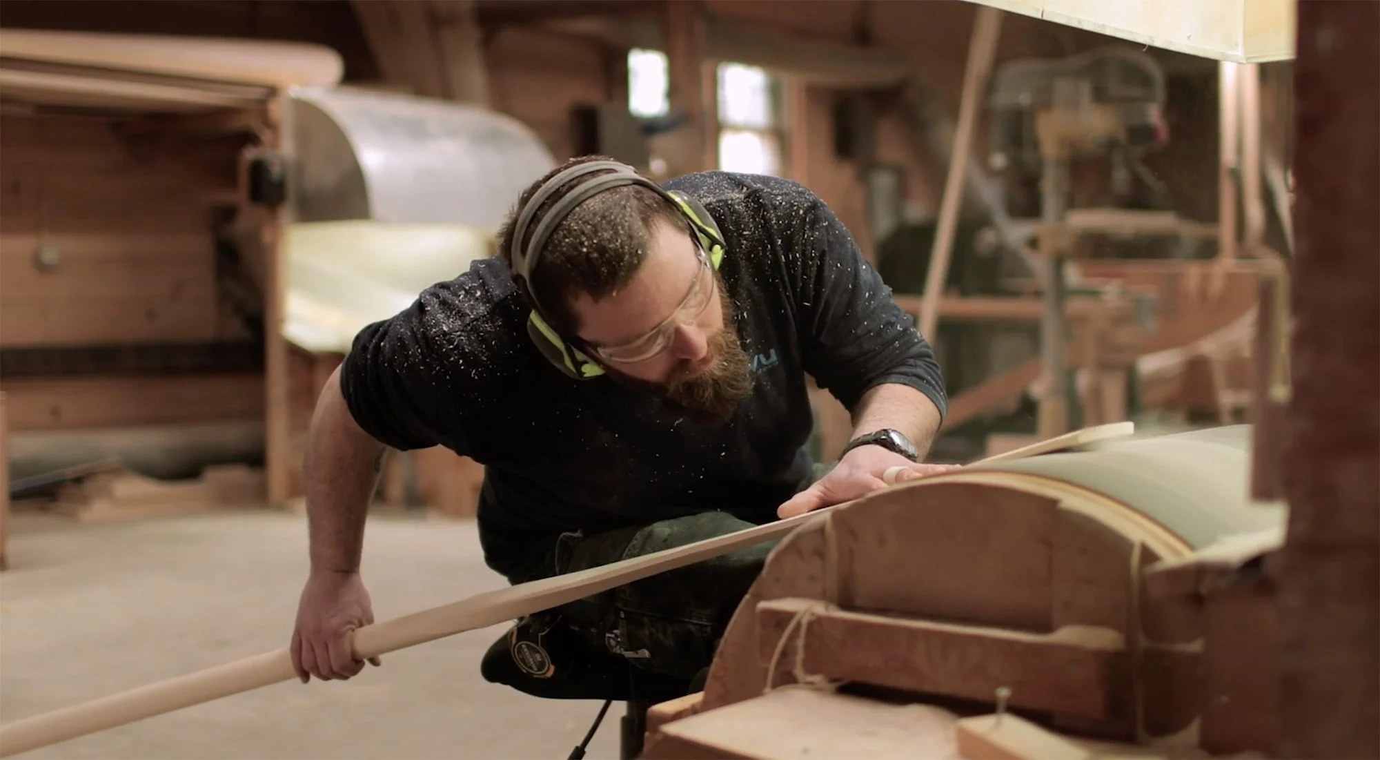 Craftsman shaping a wooden canoe paddle in Shaw & Tenney workshop, Maine