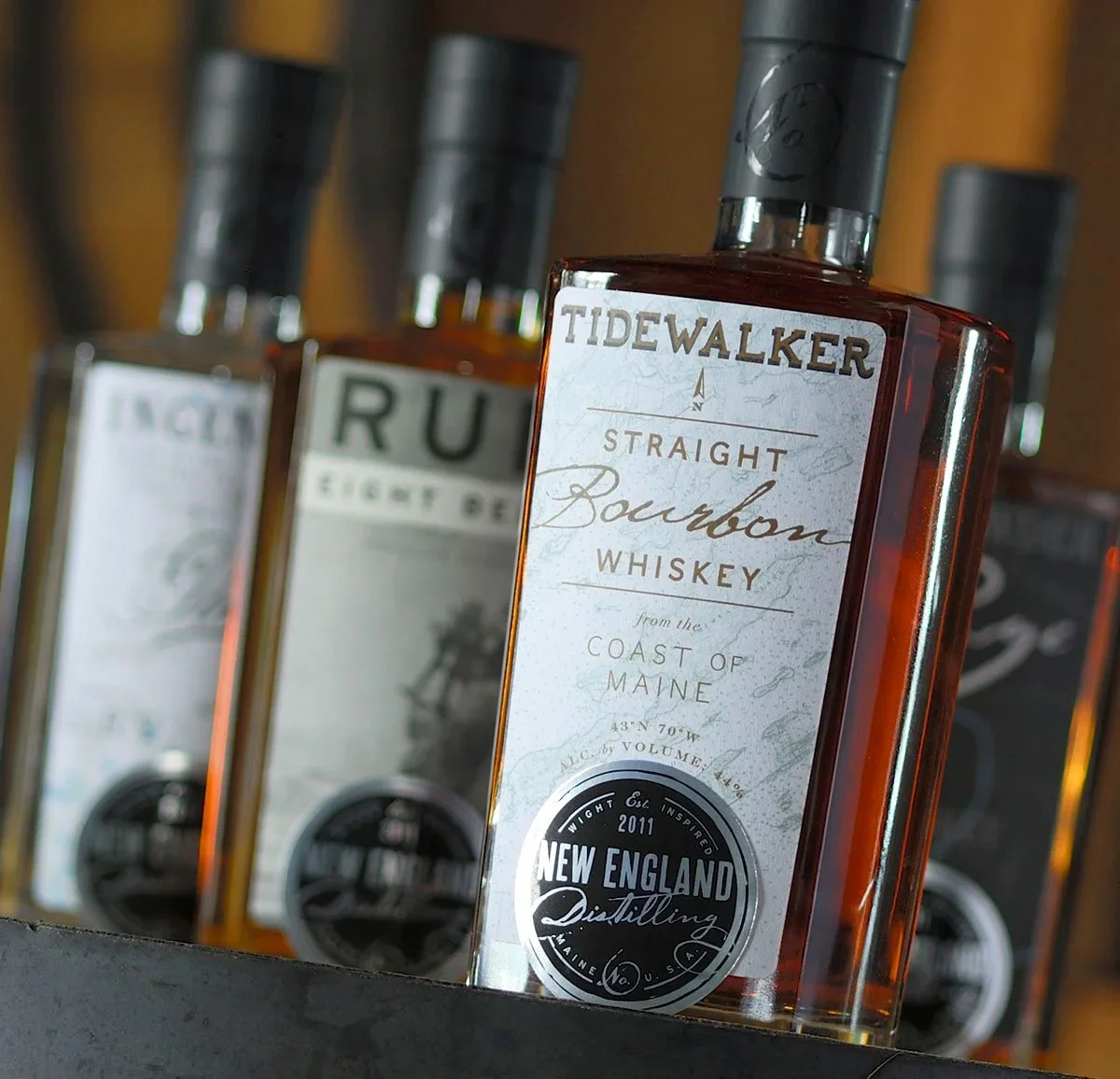 New England Distilling whiskey bottle lineup showcasing heritage spirits identity and packaging system.