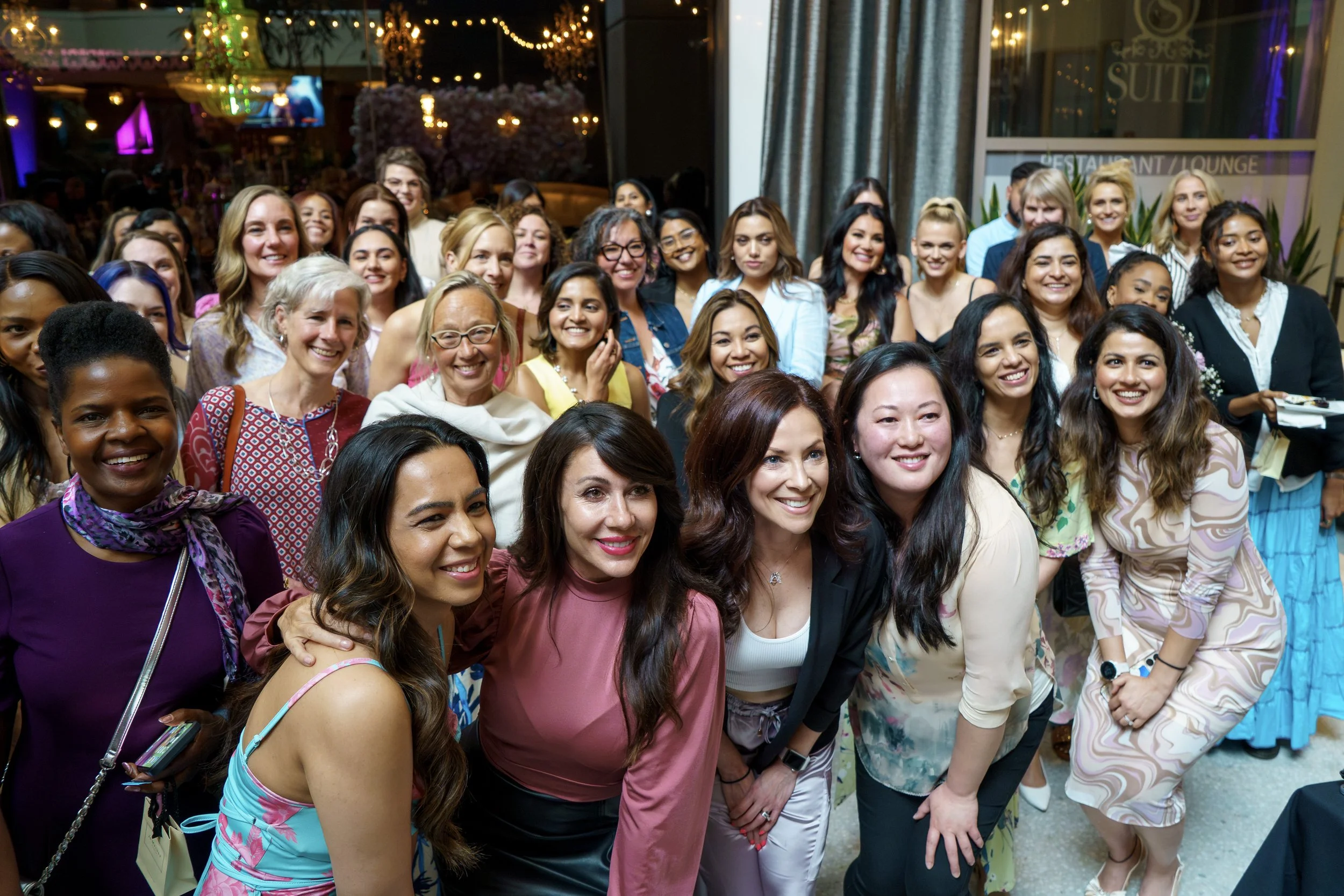 Group of smiling women at a social event or gathering at night.