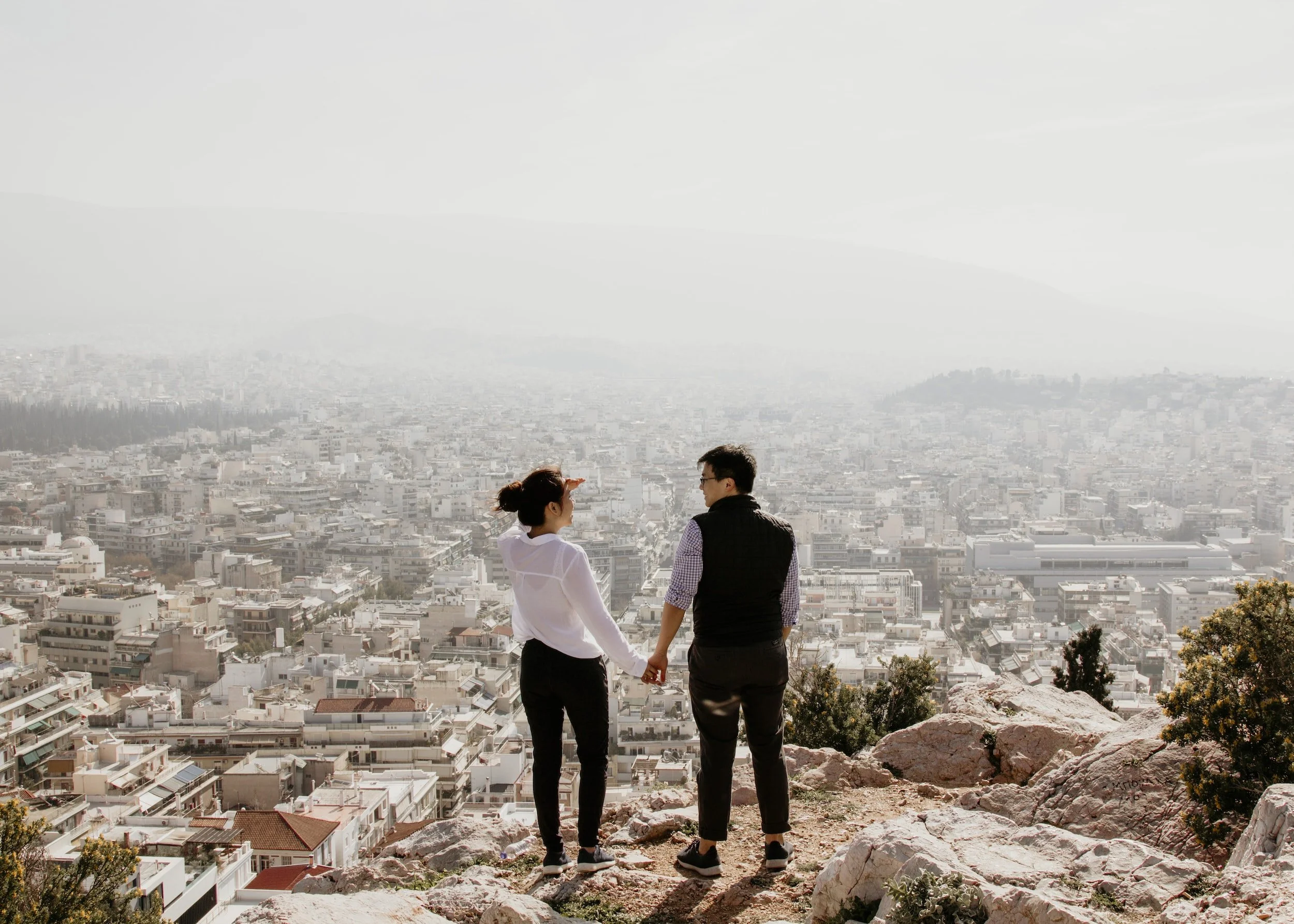 man holding woman's hand overlooking a city