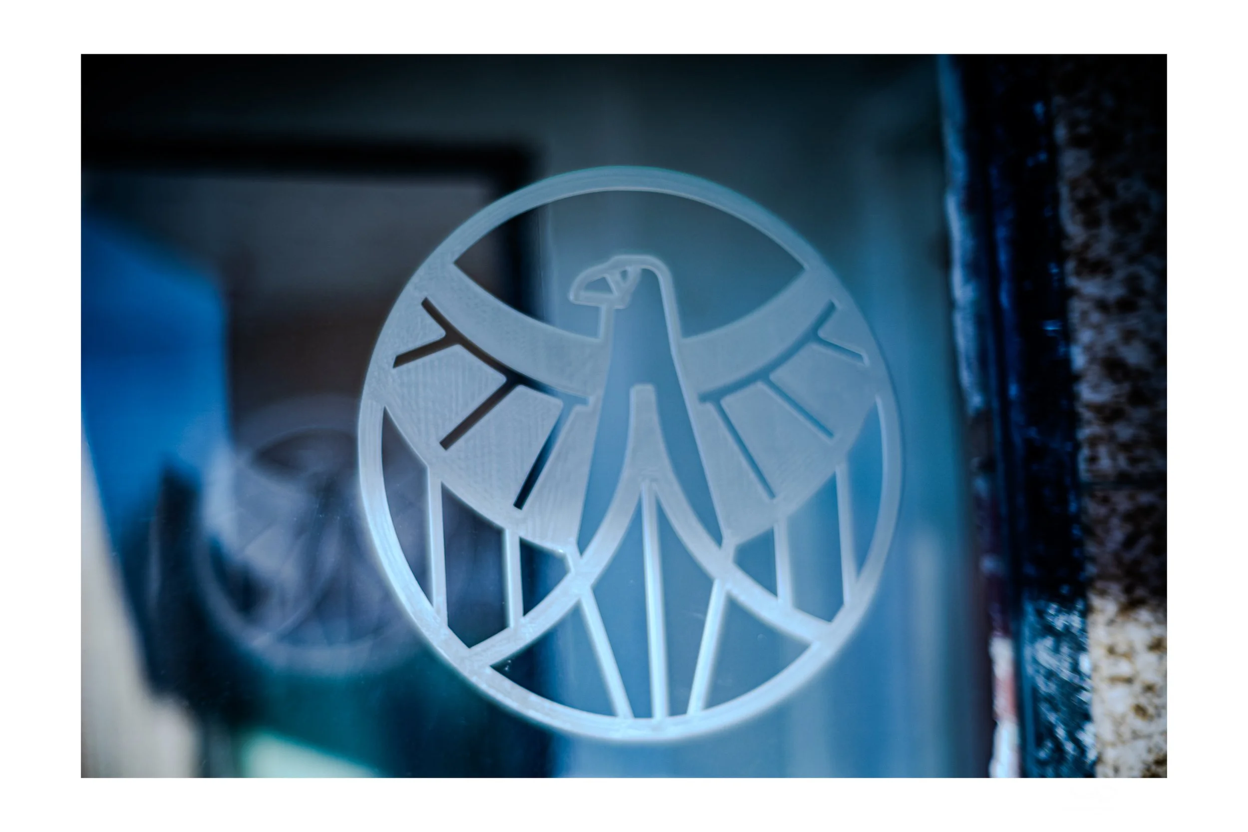 A minimalist shot of a frosted glass door with an eagle insignia, reflecting a modern yet understated element of design. Captured by ScottyD, a Dayton photographer blending fine art with local storytelling.
