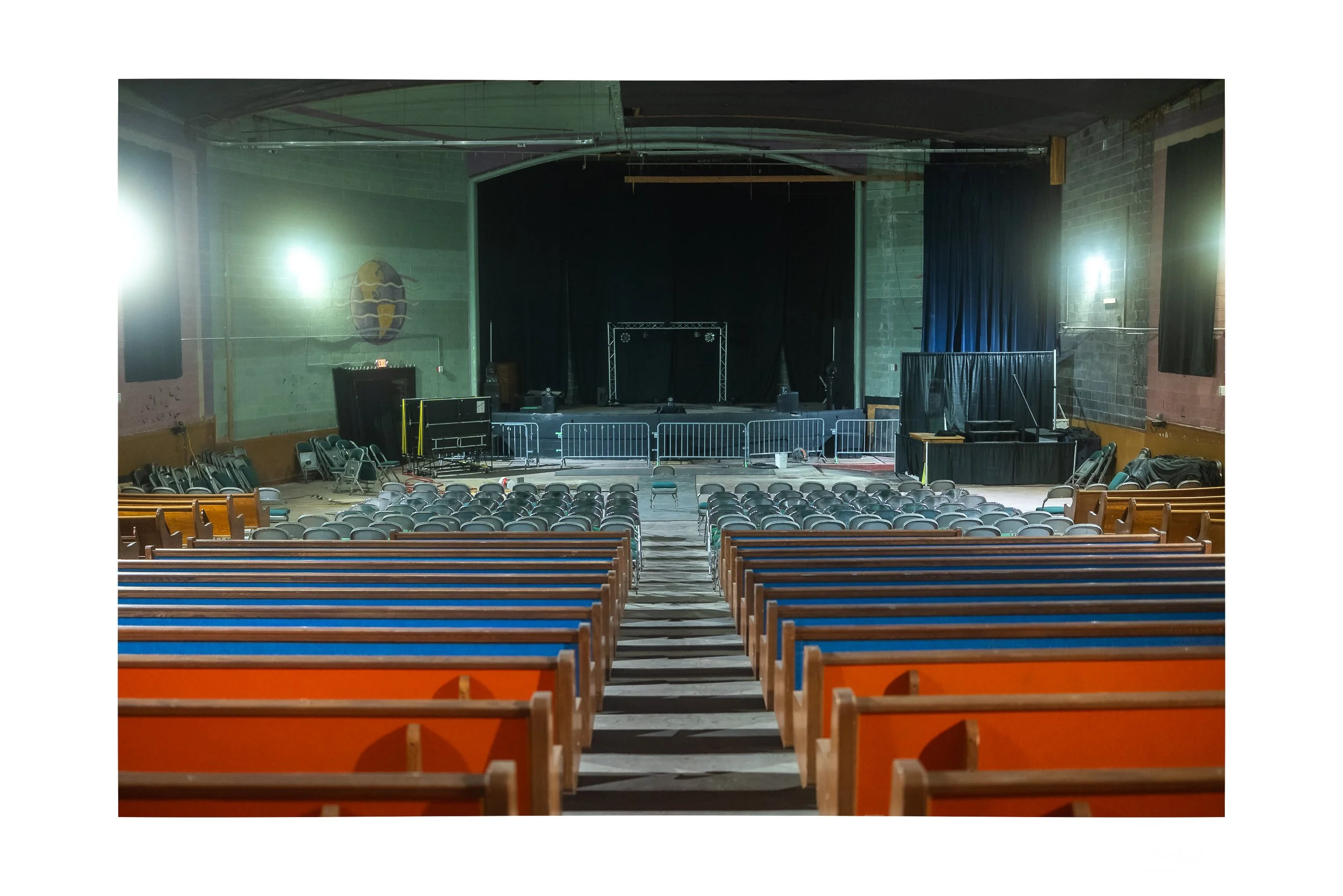 The grand, slightly worn interior of a vintage Dayton theater with rows of folding chairs and a ladder leaning near the stage.