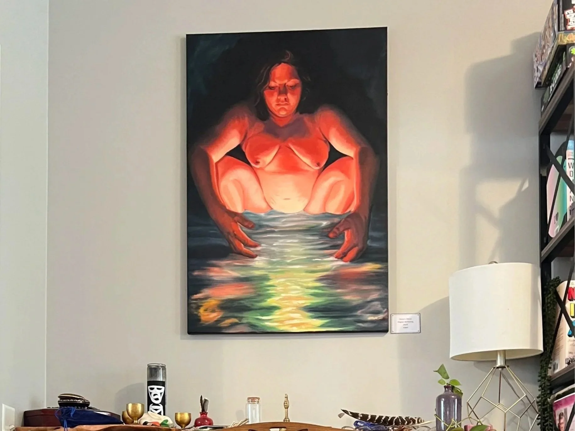 Large figurative painting of a crouching nude woman above a table in a home interior
