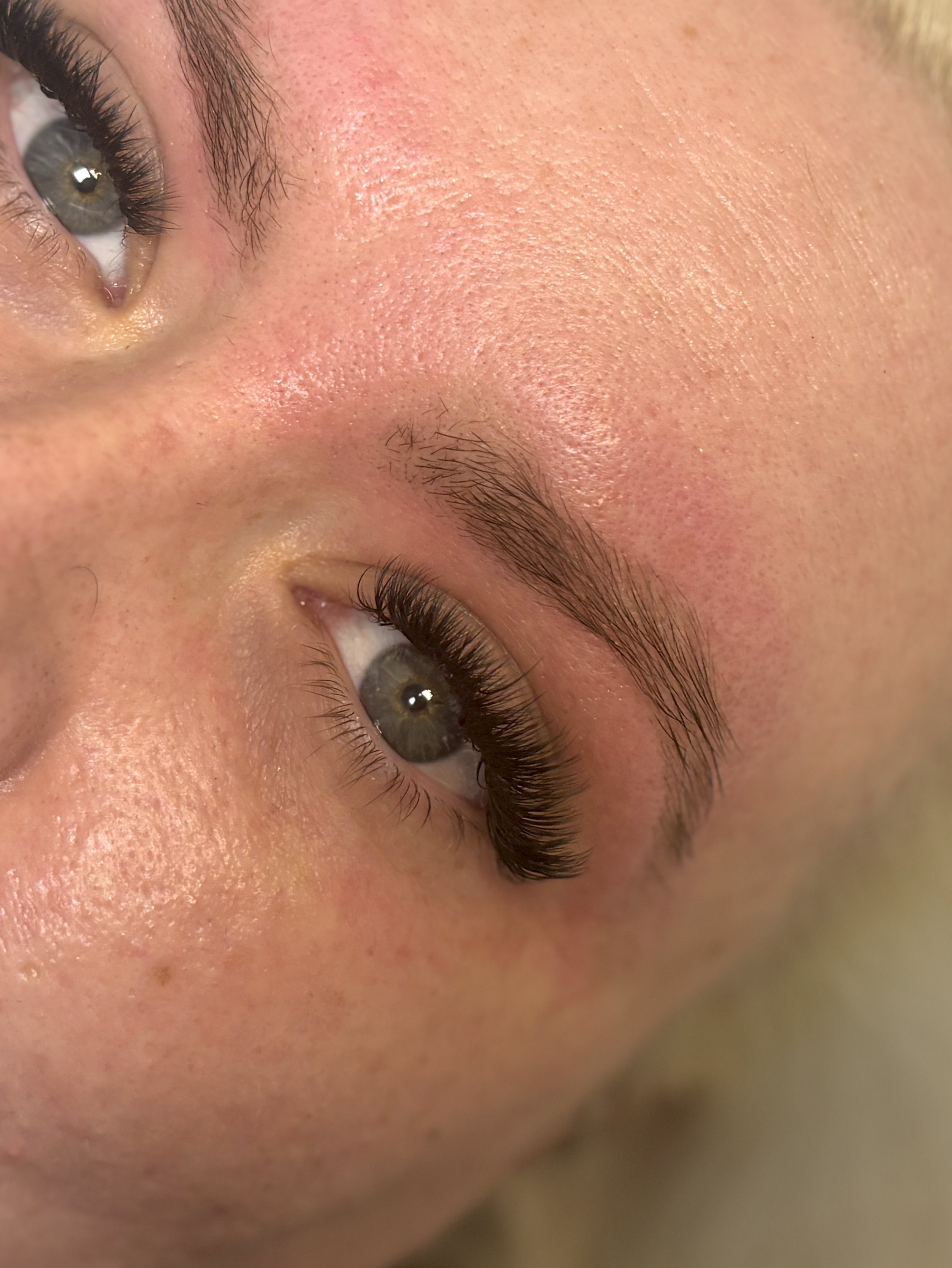 Close-up of a person's face showing green eyes, short eyelashes, and well-groomed eyebrows.