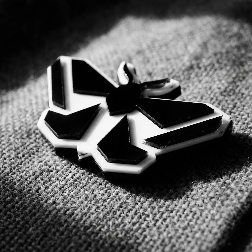 Black and white photograph of a broken Nazi swastika badge lying on textured fabric.