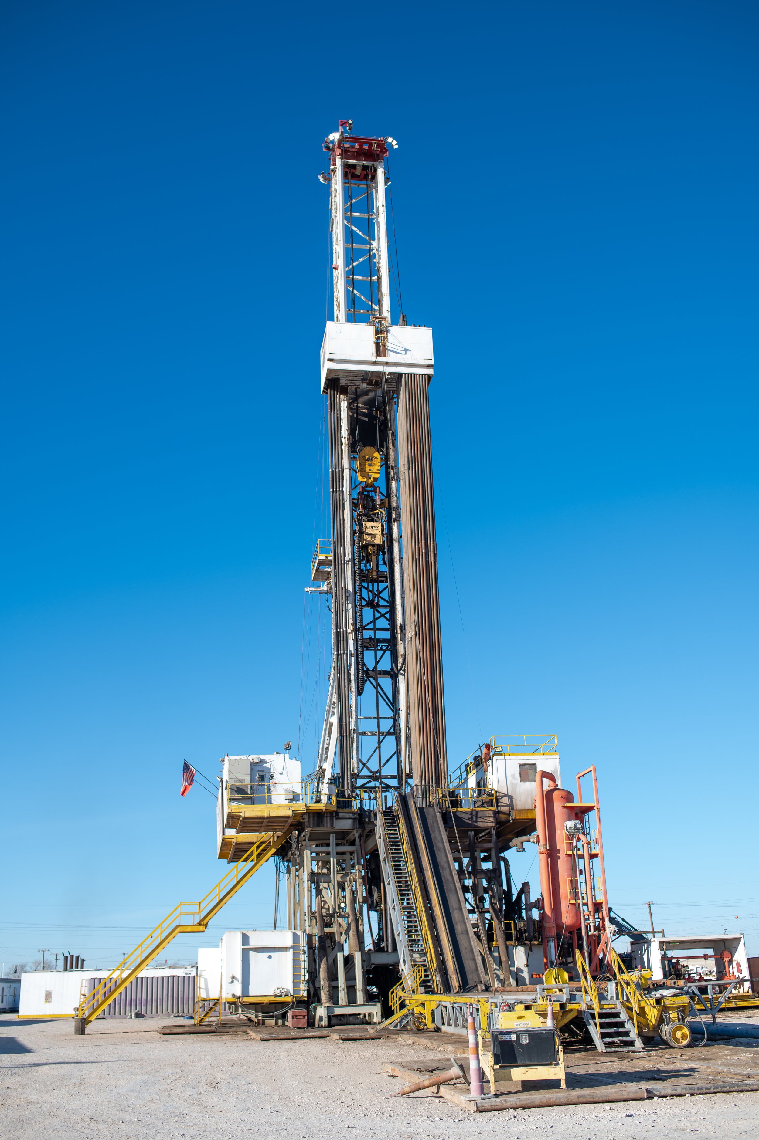 Stand-alone oil drilling rig on a clear day with a blue sky.