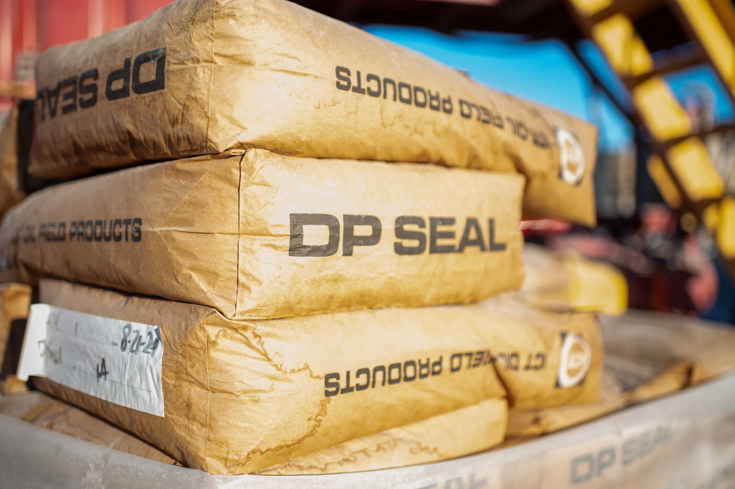 Stacks of brown paper bags labeled 'DP SEAL' and 'CEMENT PREMIXED PRODUCTS' on a worksite