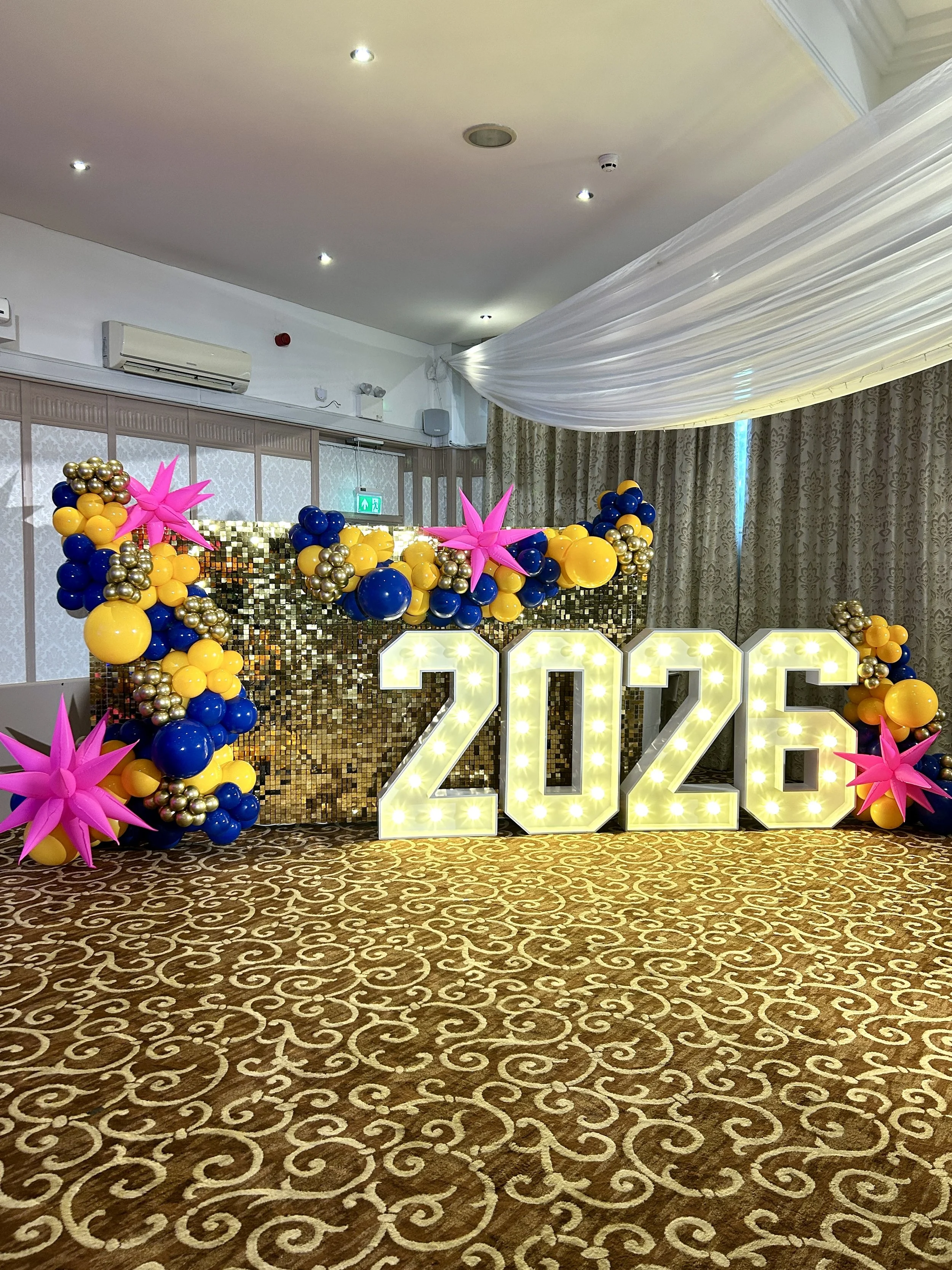 light up 2026 numbers with gold shimmer wall and yellow and blue balloon garland at there felbridge hotel in east grinstead 