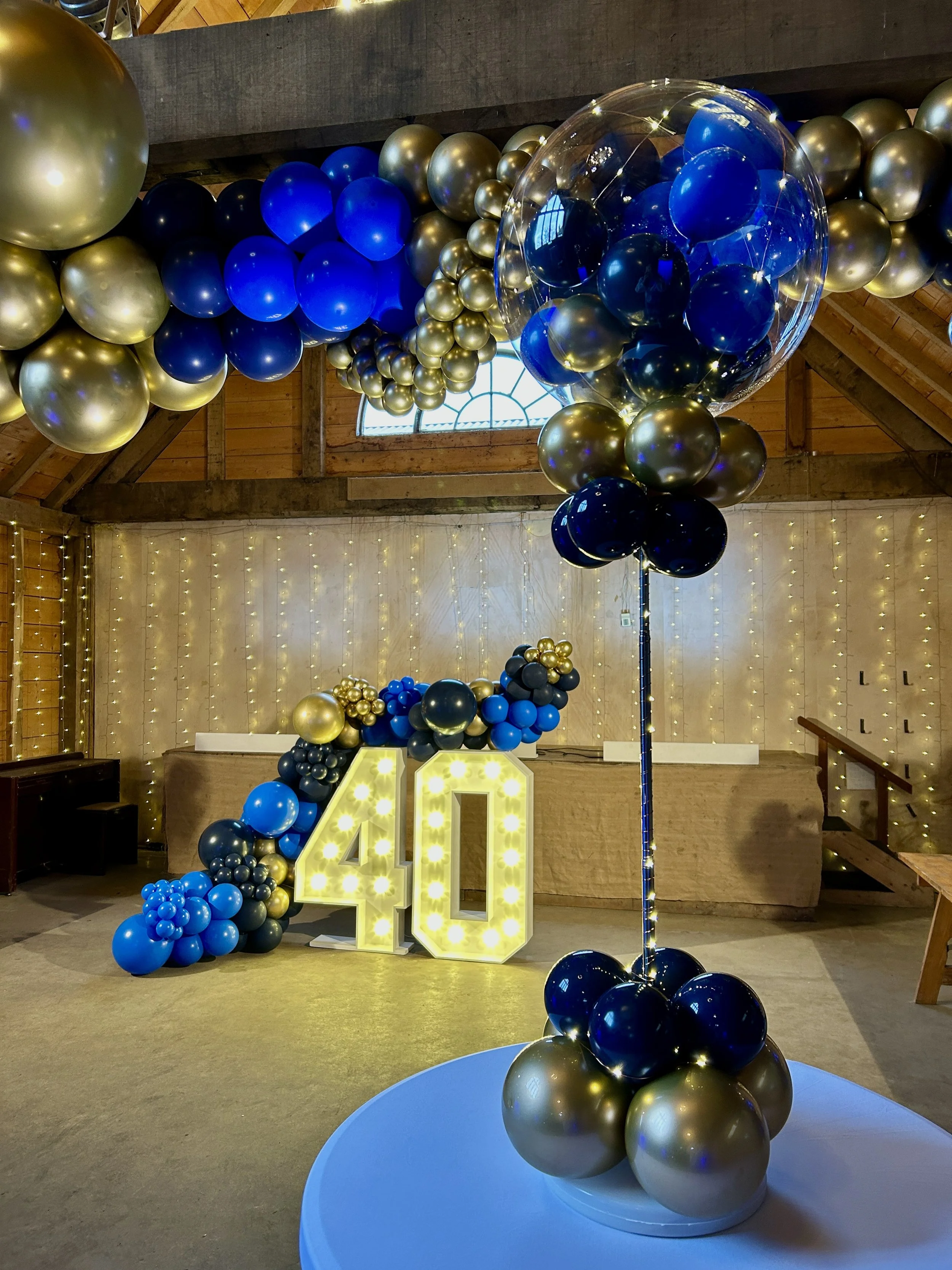 blue gold and navy balloon garland with matching table balloon centrepieces