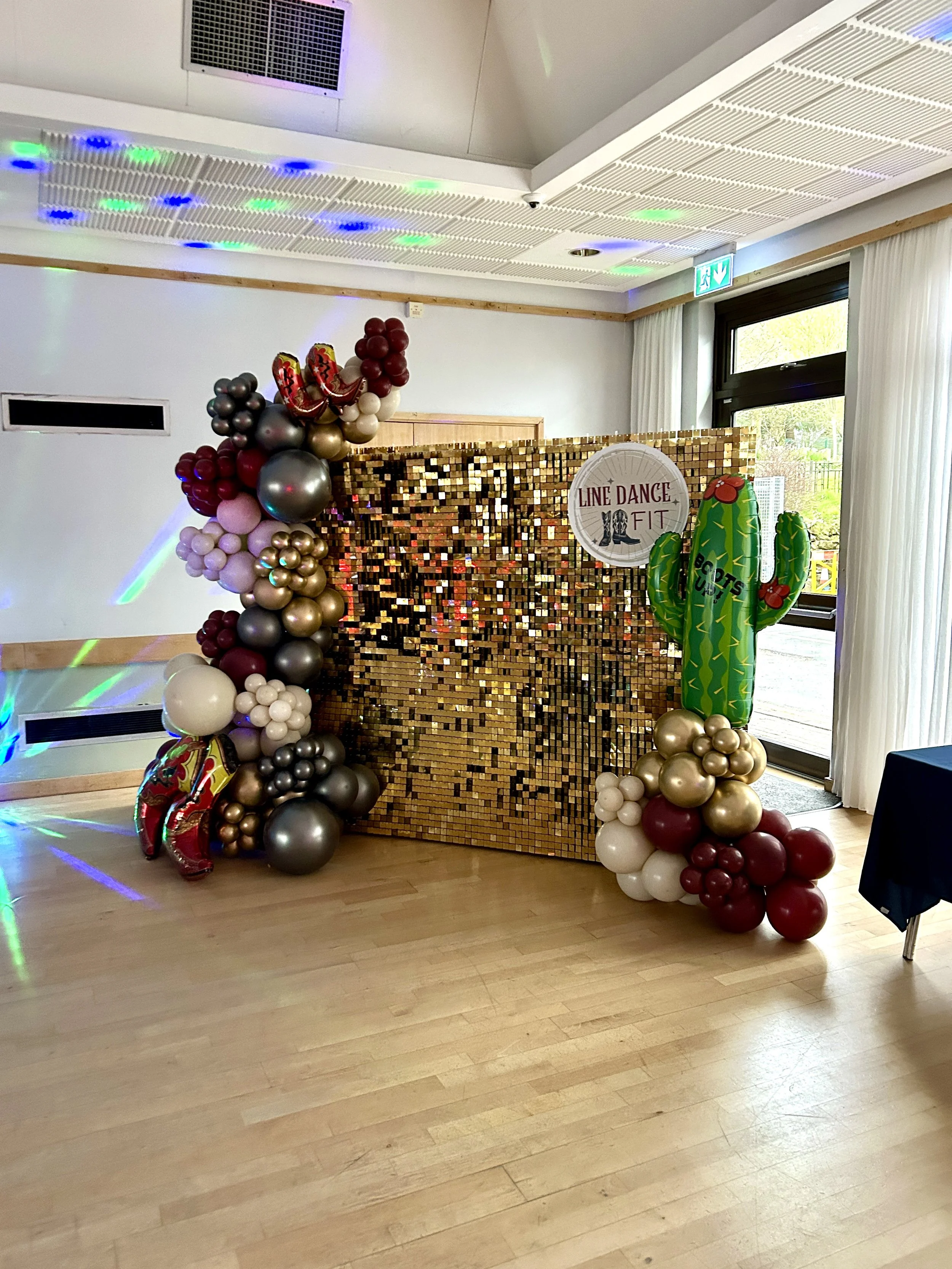 gold shimmer wall with red grey and cream balloon garland for a line dancing event in east grinstead 