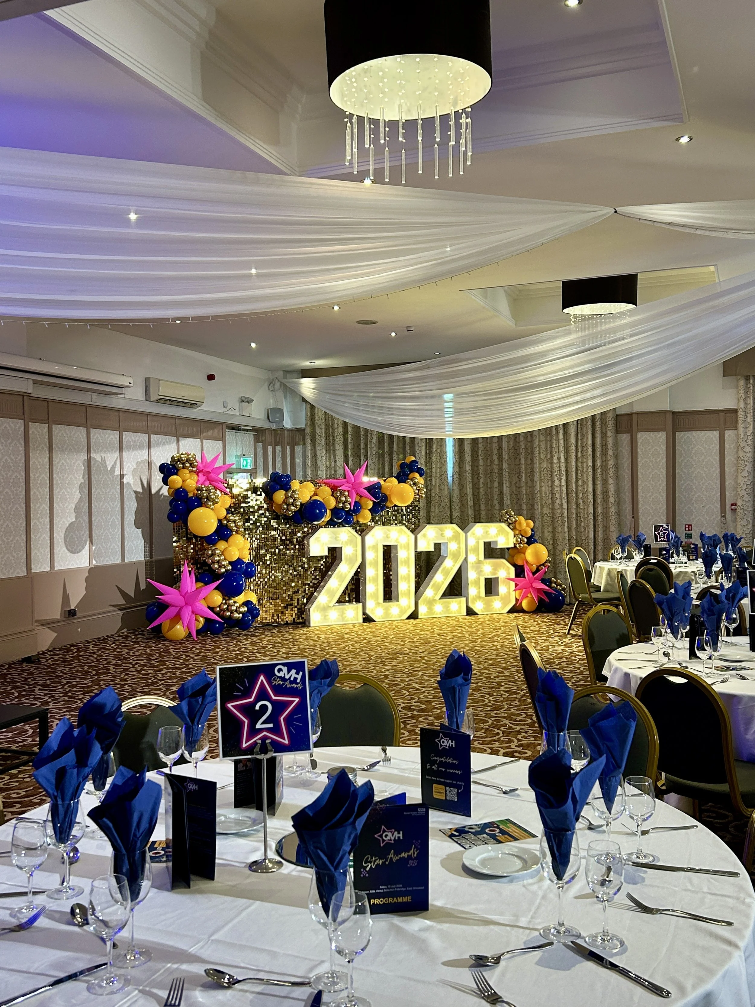corporate event balloon backdrop with gold shimmer wall light up numbers and balloon garland at the felbridge hotel in east grinstead fir the queen victoria hospital 