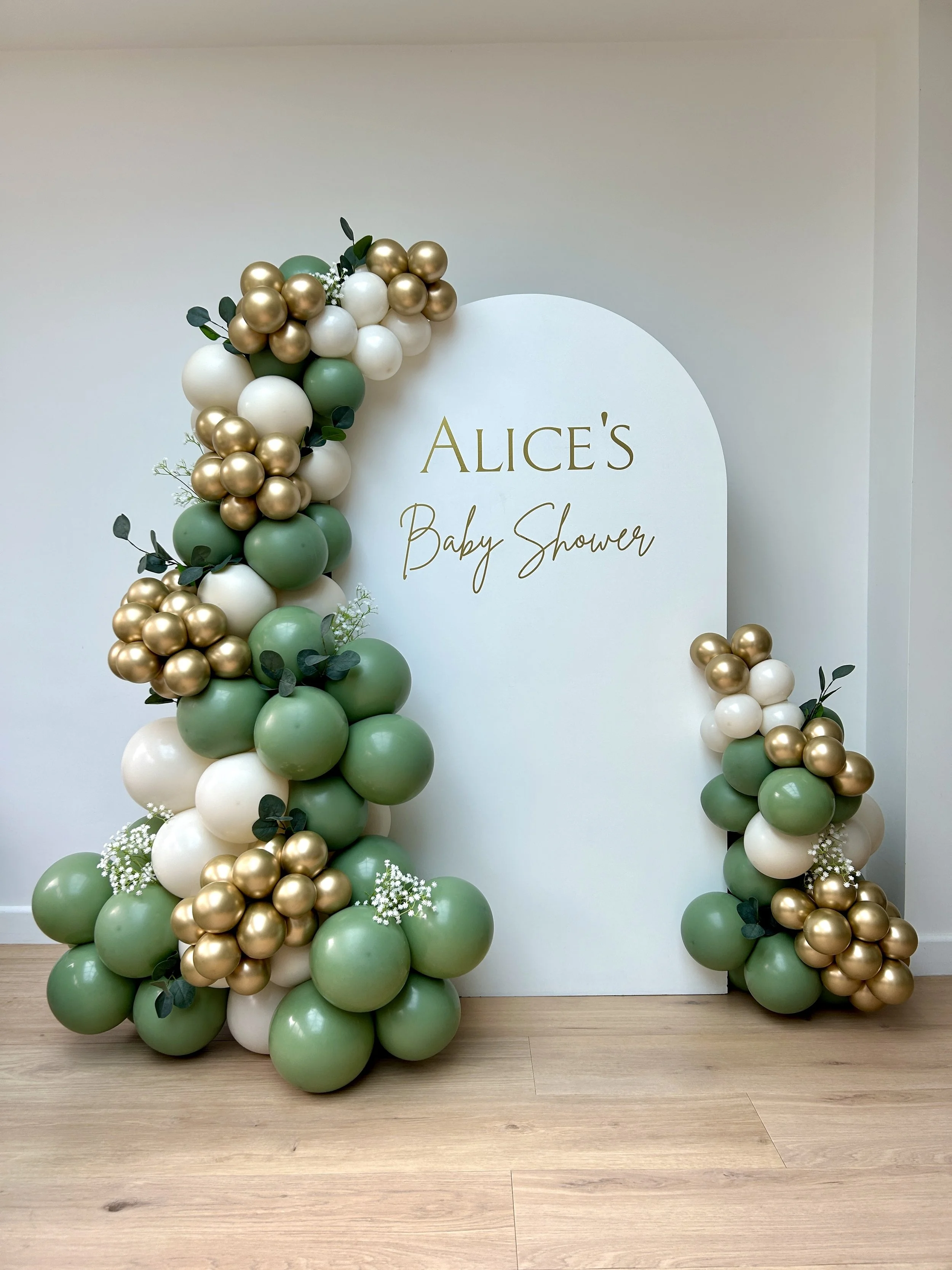 Baby shower styling in east grinstead sussex using a white sailboard with green cream and gold balloon garland with added foliage