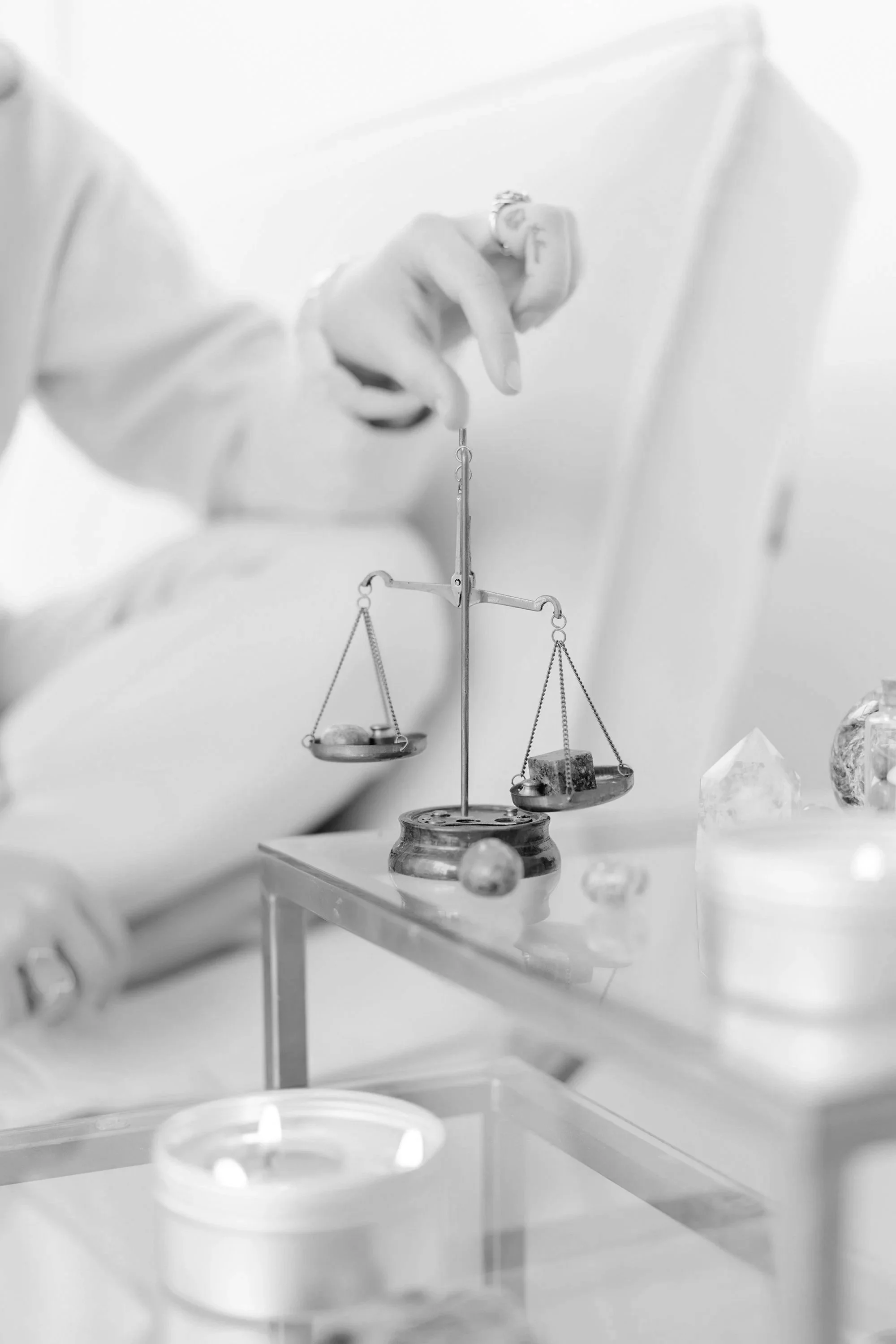 Brass balance scale with crystals, candles on glass table