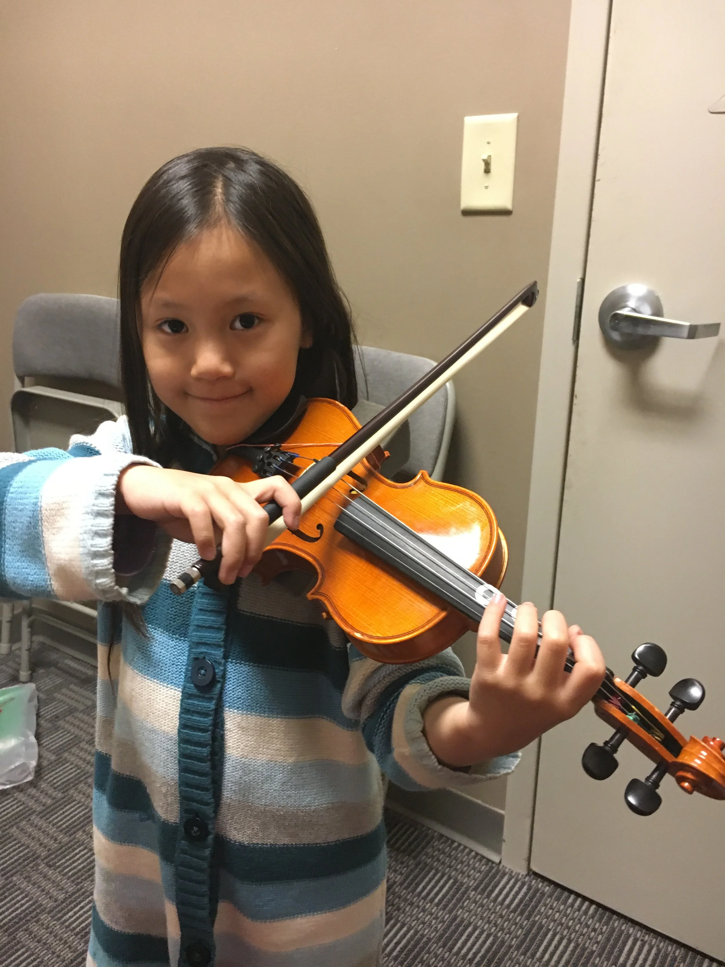 Child playing a violin indoors