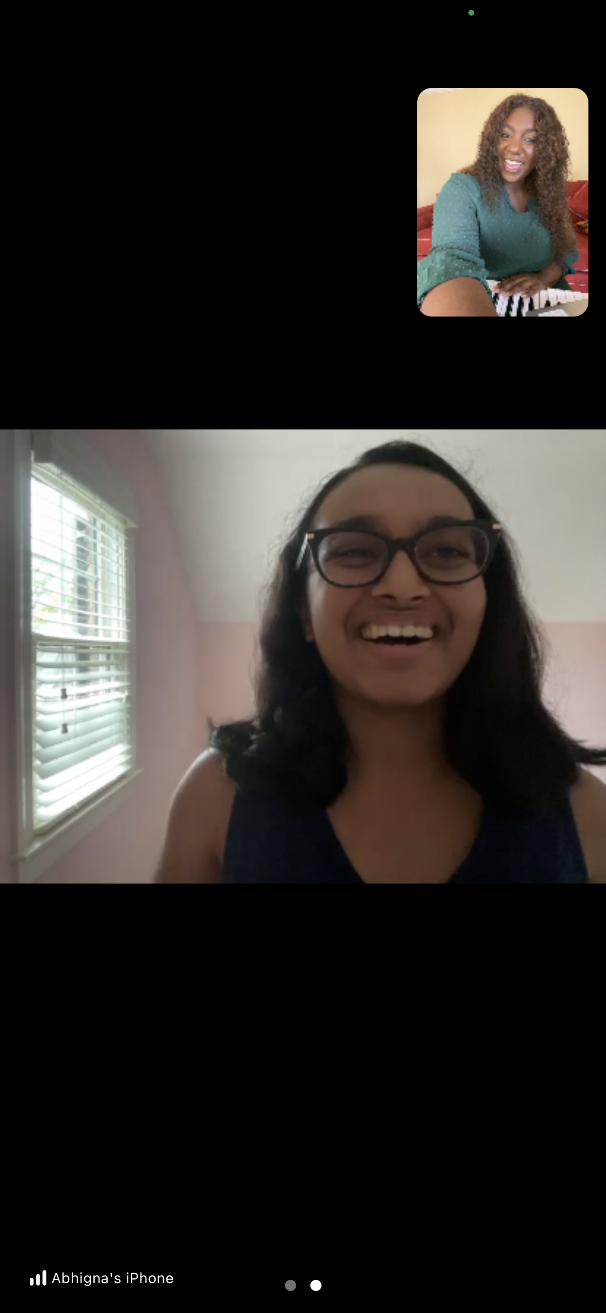 Two people in a video call smiling; one is in the main window with glasses, the other in a smaller window, wearing a green shirt.