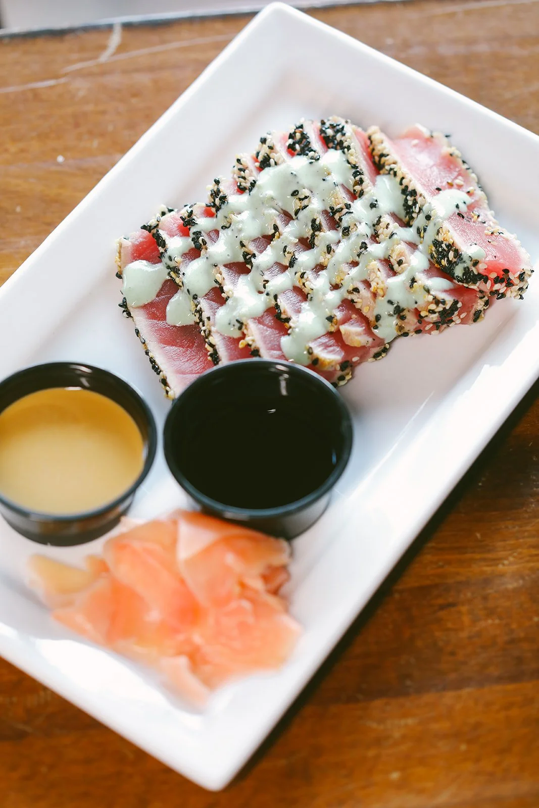 Slices of fresh seared tuna with a light garnish on a modern appetizer plate