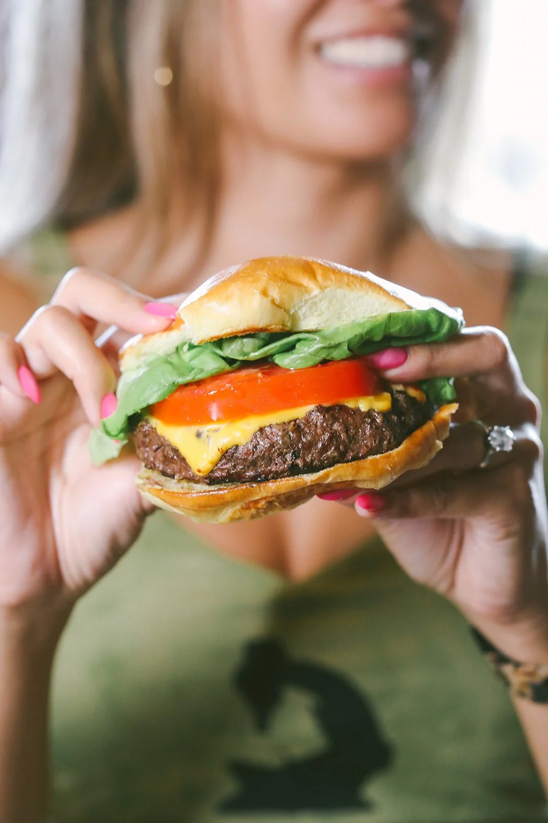 Juicy cheeseburger with melted cheese, lettuce, tomato, and onion on a toasted bun