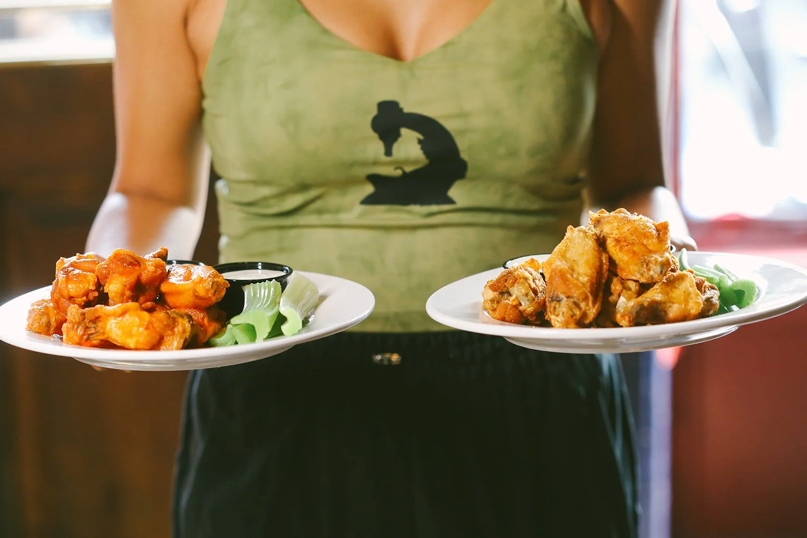 Server presenting a tray of spicy buffalo wings alongside old bay seasoned wings