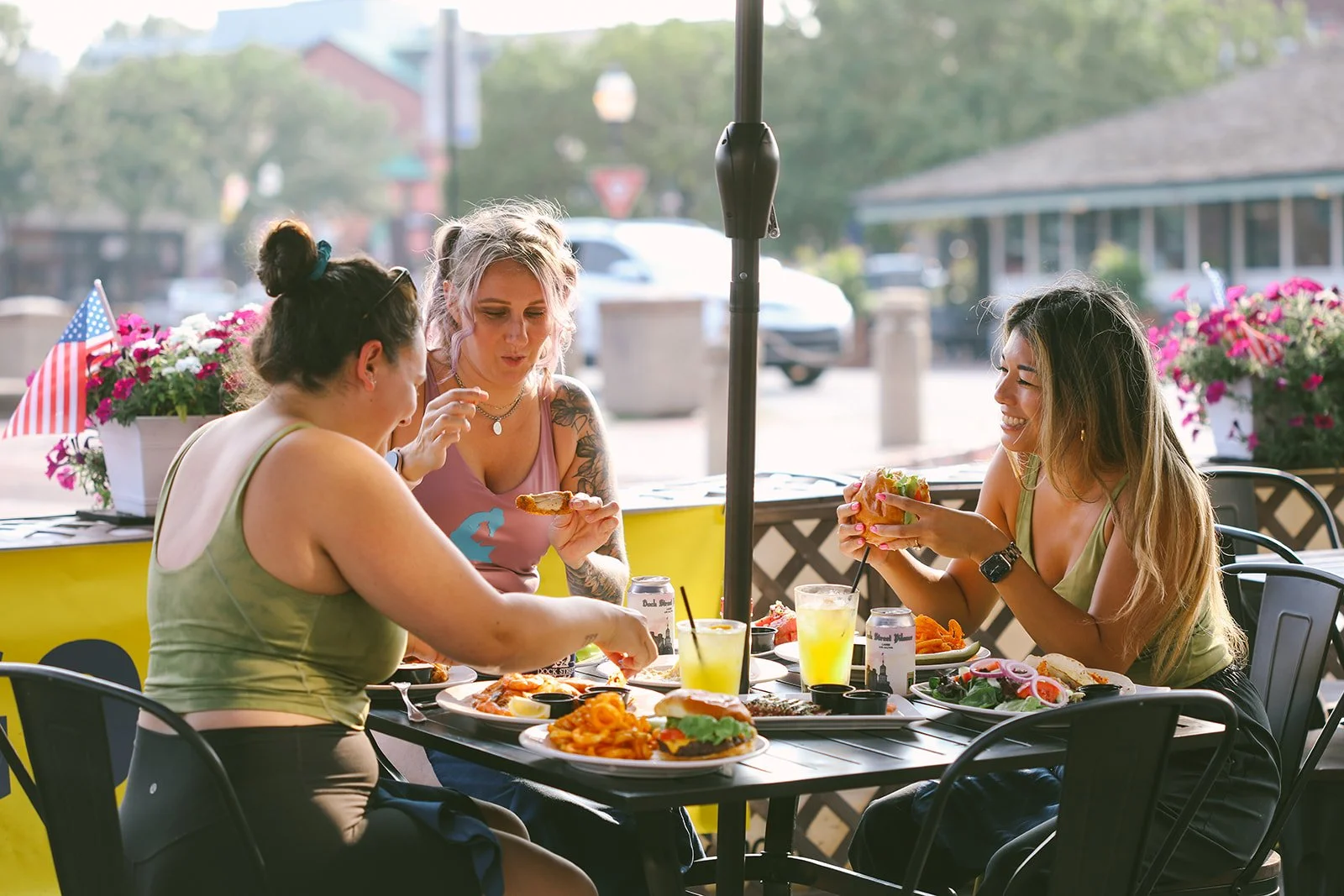 Three ladies laughing and enjoying delicious food and drinks by the waterfront at Ego Alley in downtown Annapolis