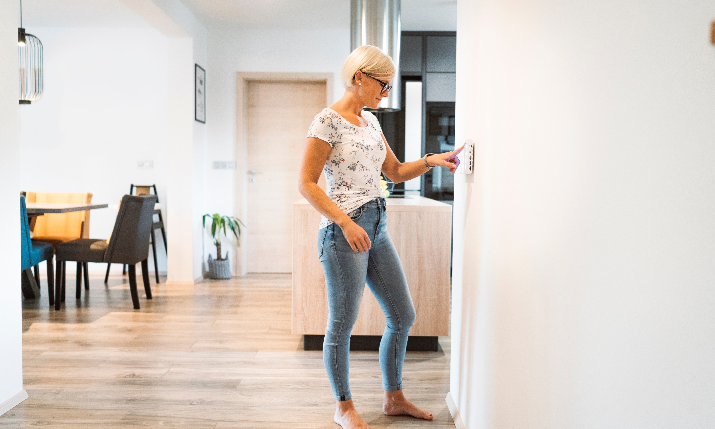A woman uses her smart thermostat at home.