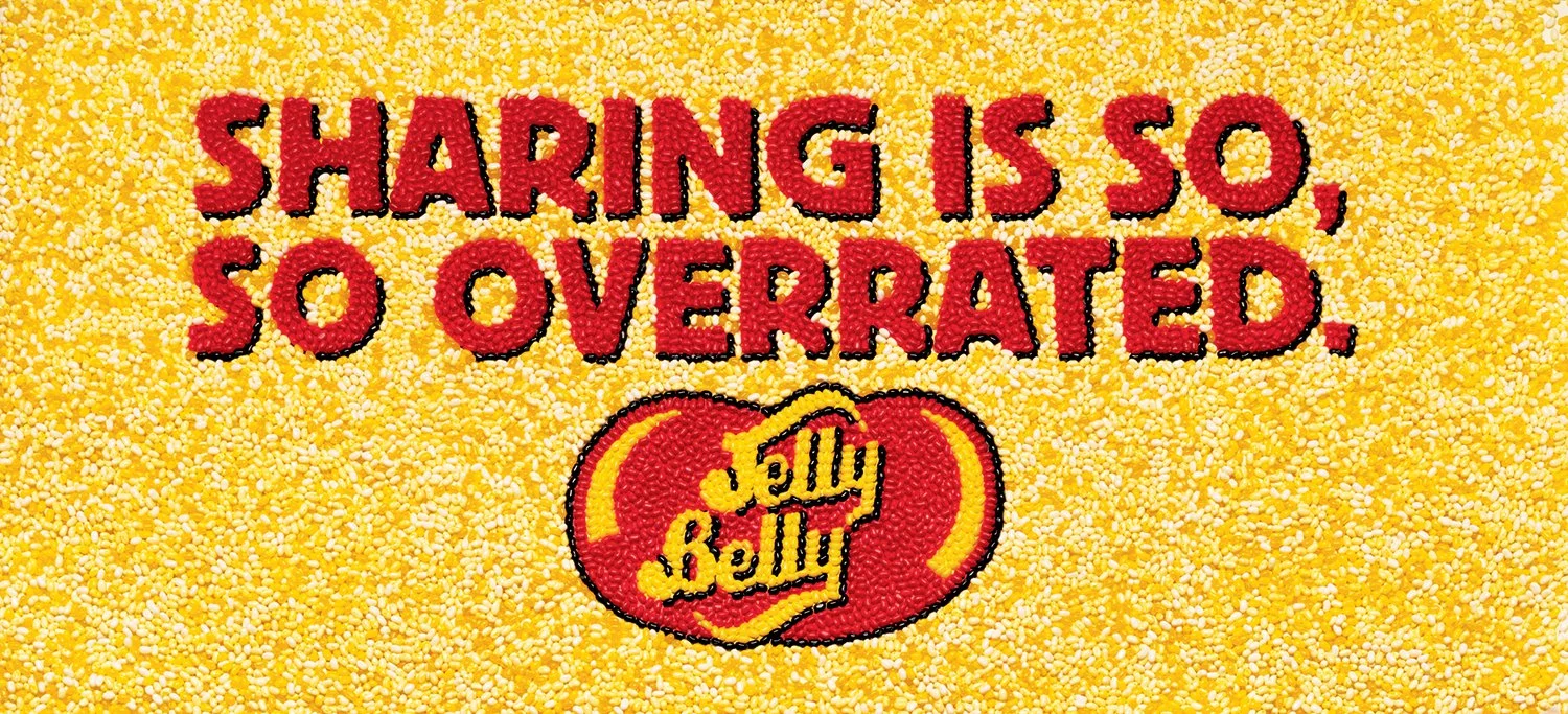 Billboards made of Jelly Bellies glued together (no AI). Headline reads "Sharing is so, so overrated."