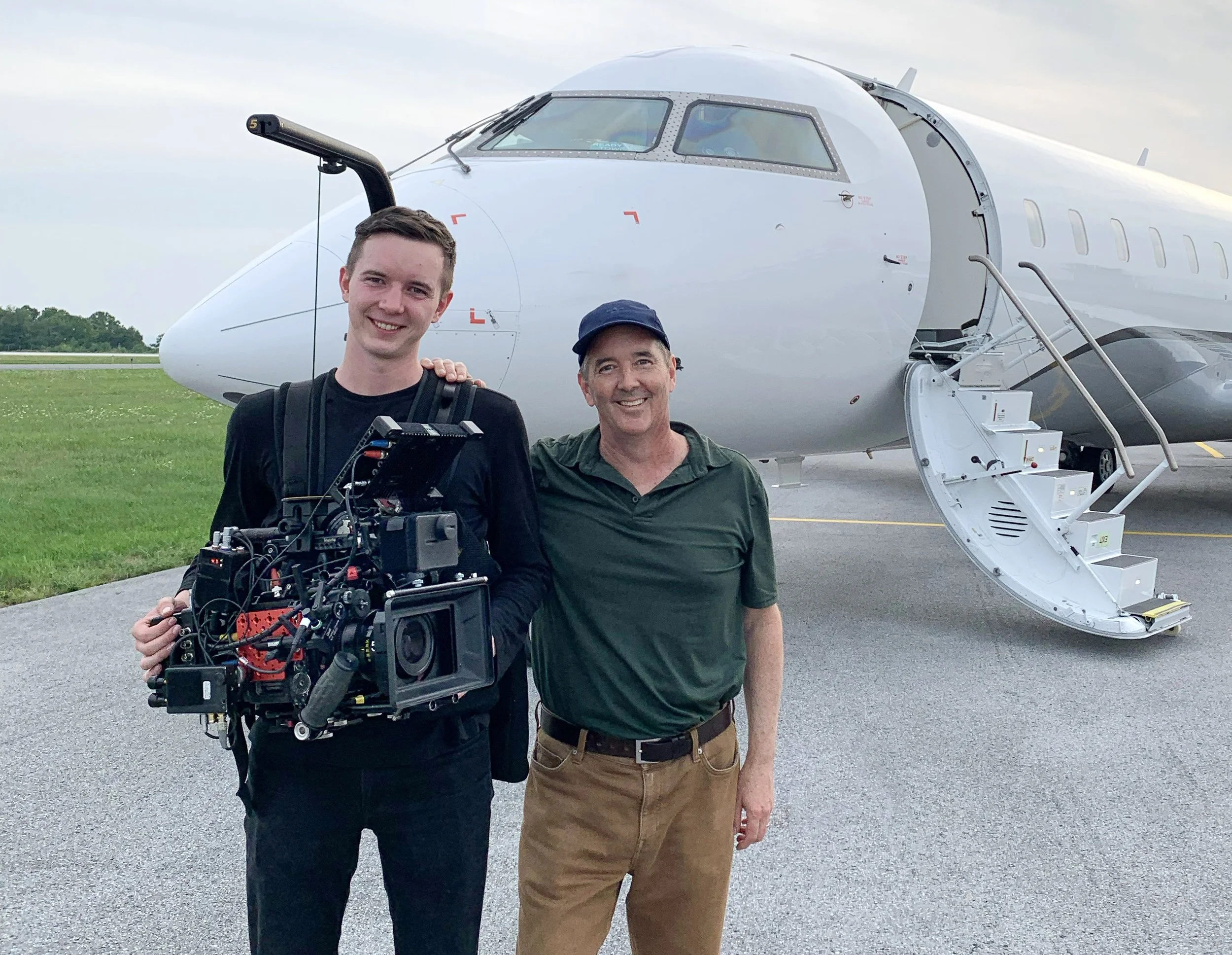Swope Films director and creative director David Swope with cinematographer Ethan Swope standing in front of a Slate Aviation private jet airplane on an airstrip.