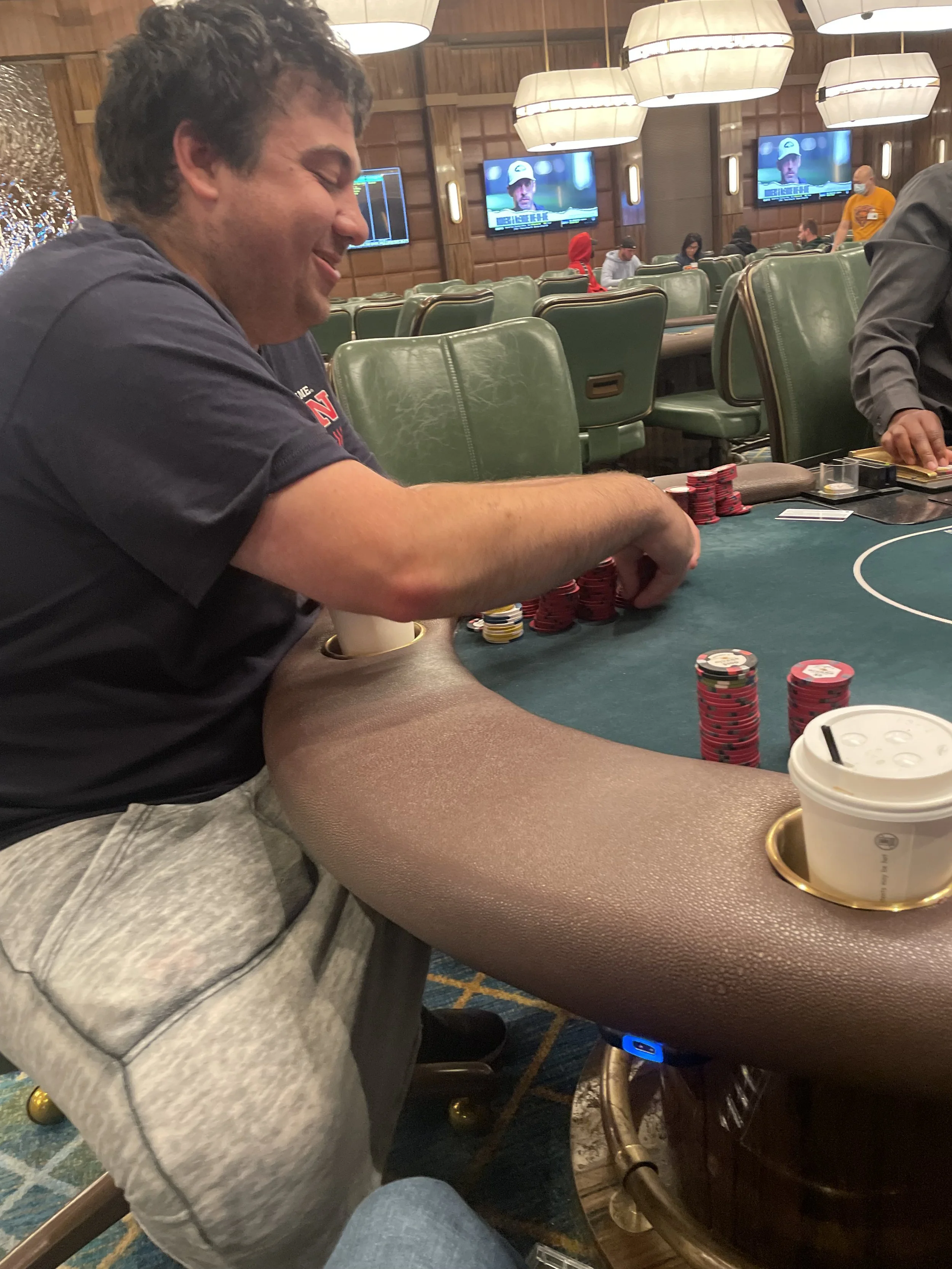 Man playing poker at a casino table with poker chips and a coffee cup.