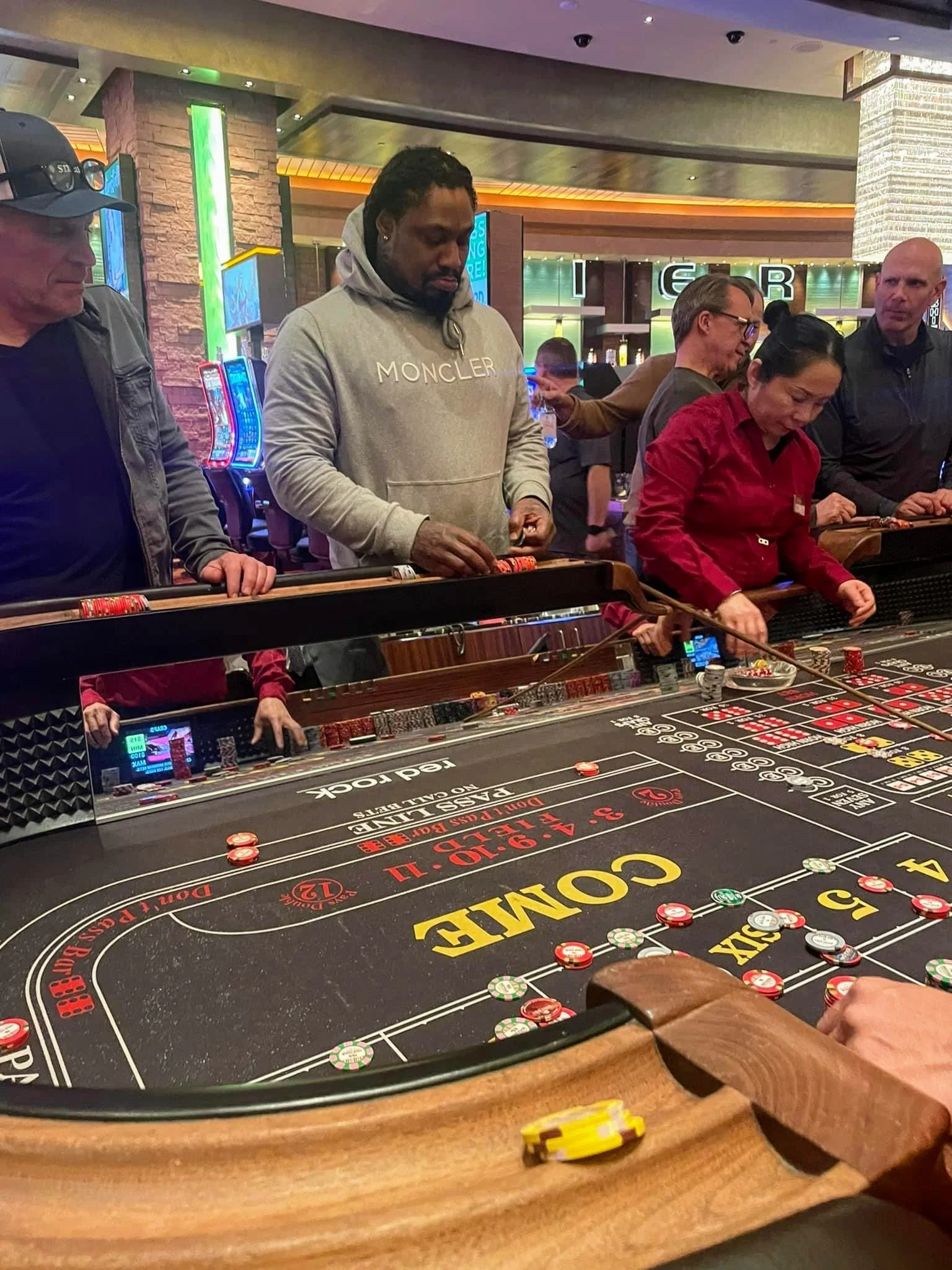 People playing blackjack at a casino table, with casino employees and players engaged in the game.