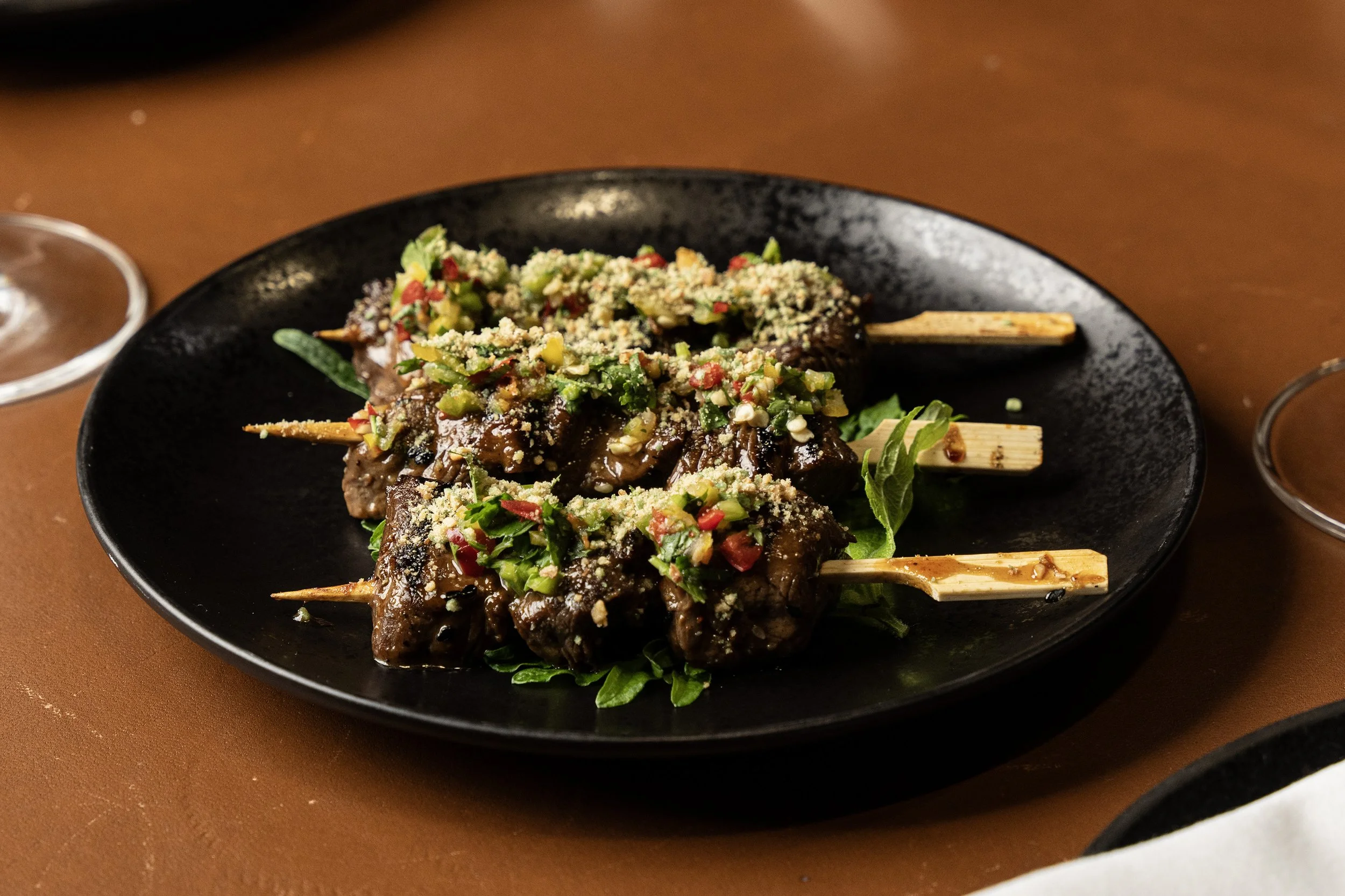 Gegrillte Fleischspieße mit frischem Gemüse und Parmesan auf schwarzem Teller