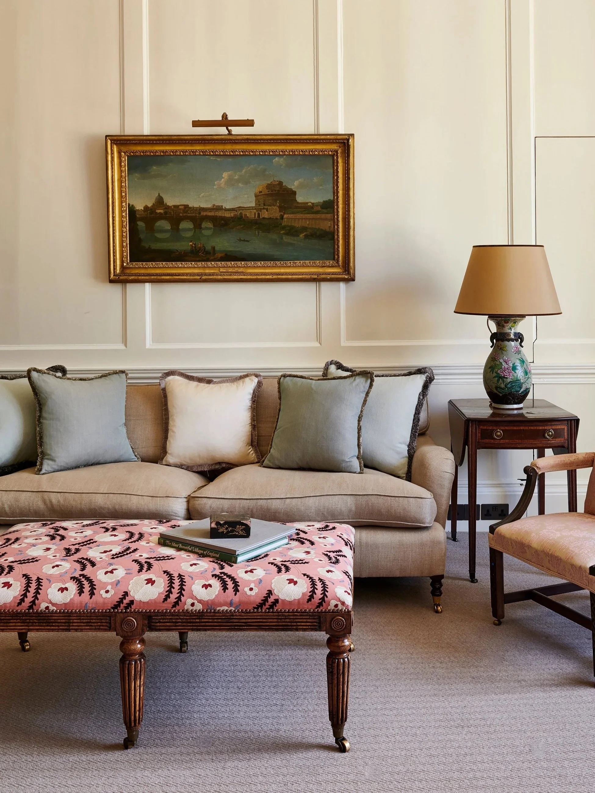 Panelled drawing room with upholstered sofa, ottoman and antique chair