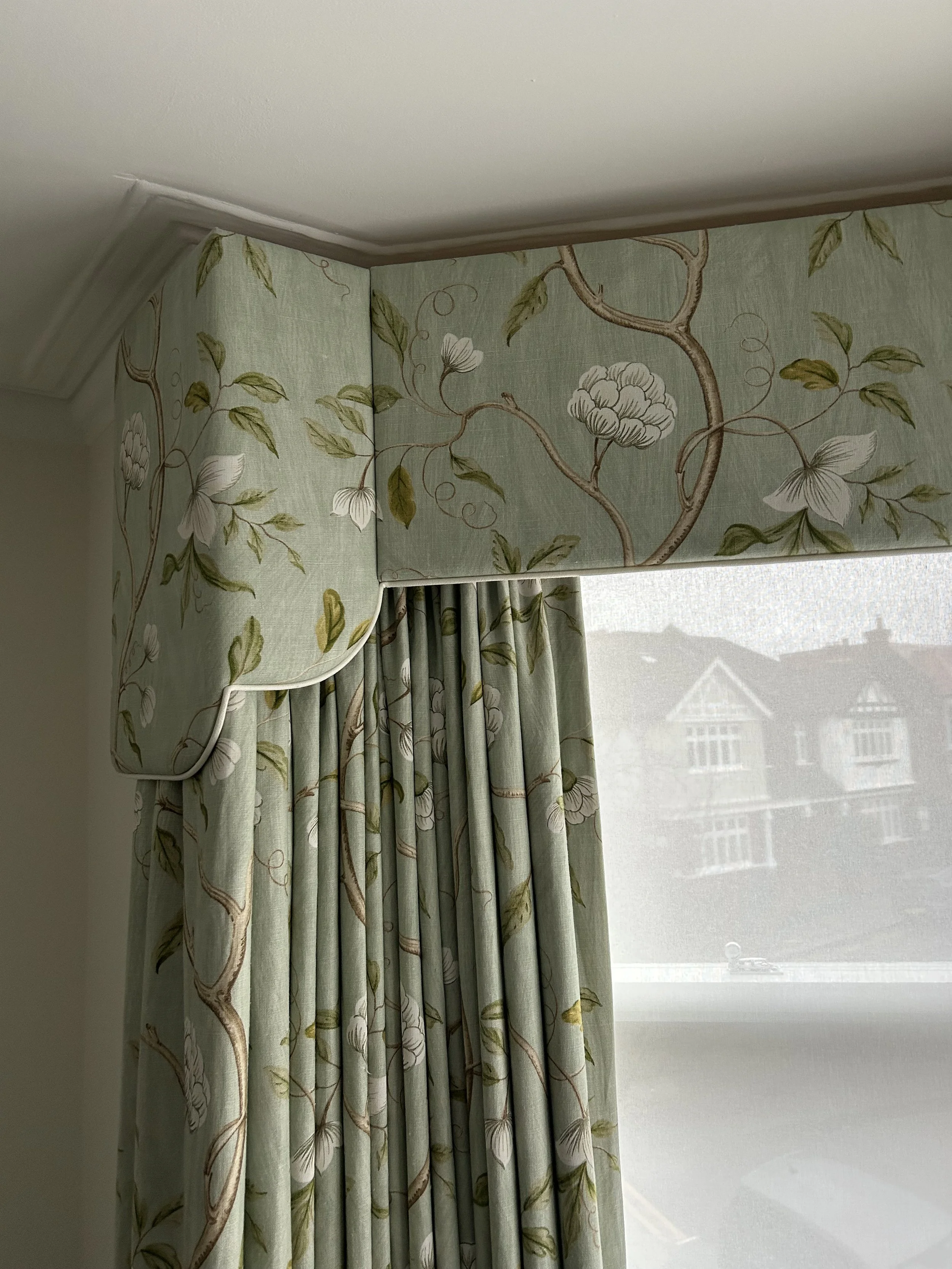 Shaped upholstered pelmet with contrast piping in a green floral linen by Sanderson, with matching curtains