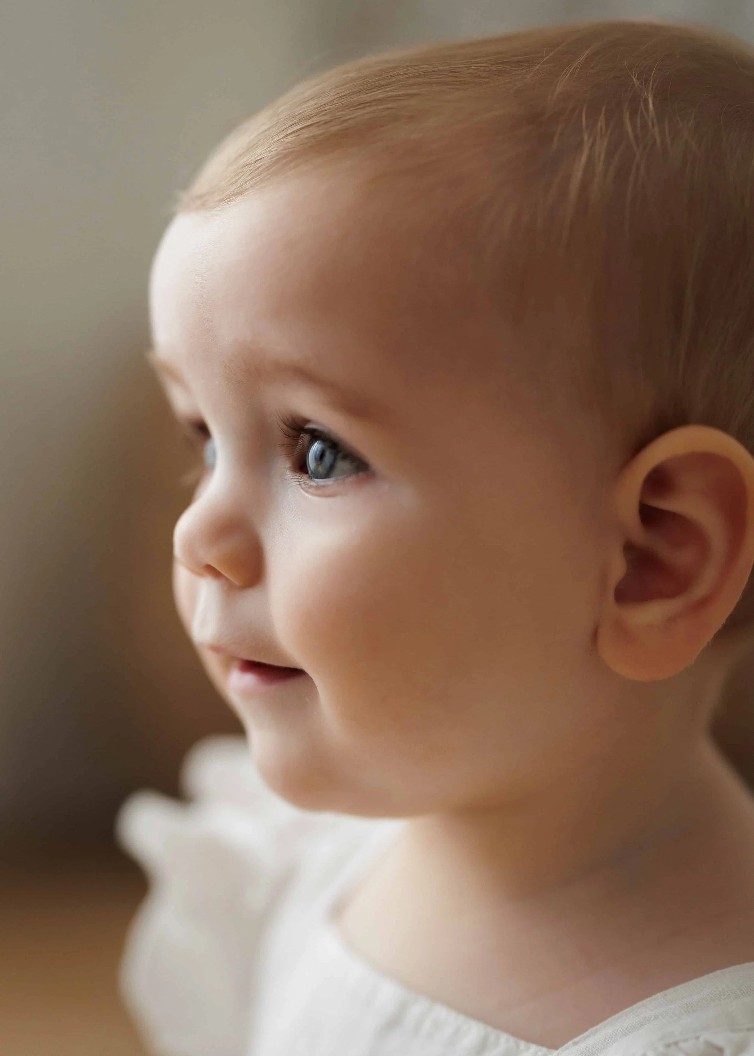 Close-up of a young child's face in profile, showing blue eyes, light skin, and light reddish hair, wearing a white shirt.