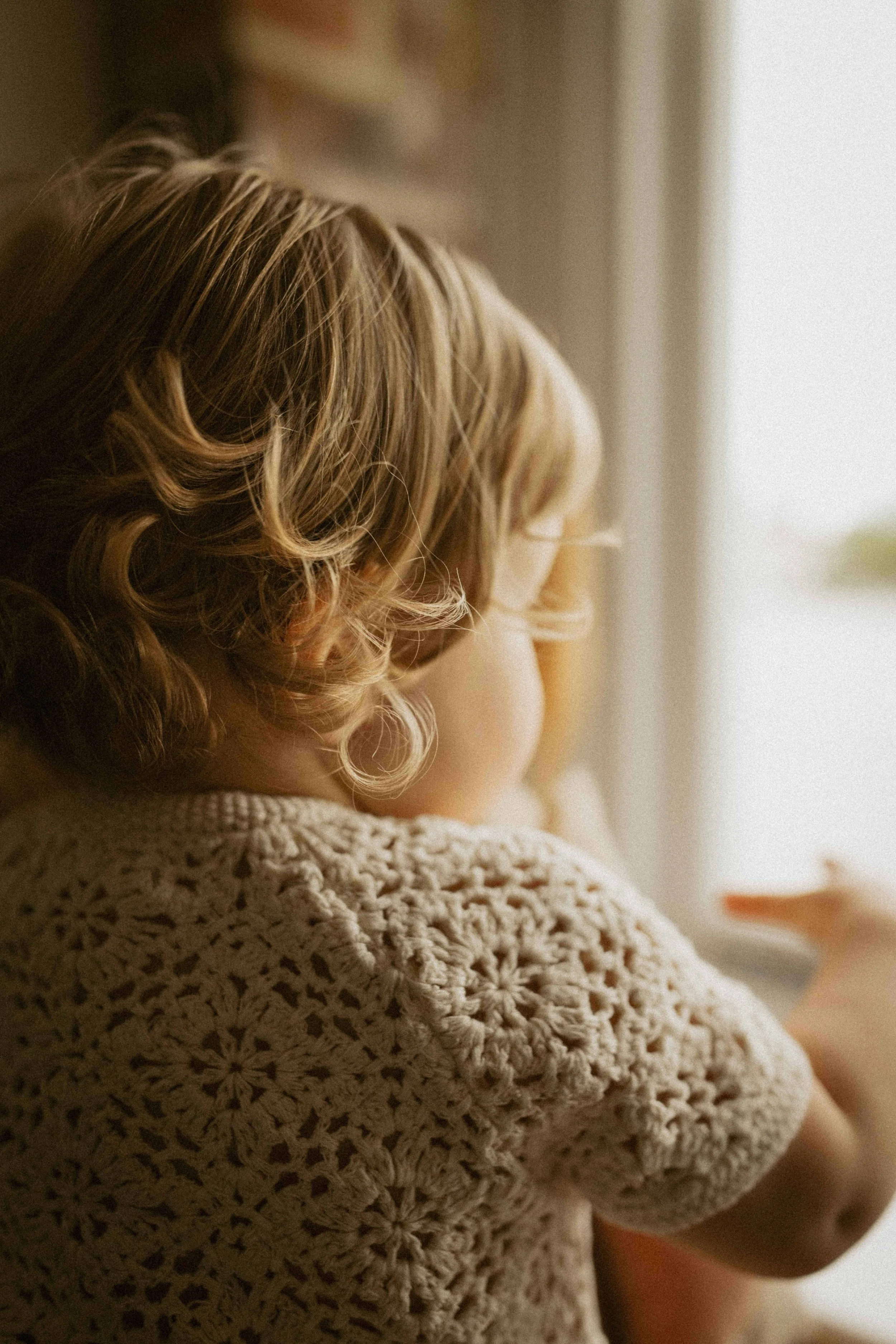 little girl with blond curly hair looking at window in london during a family photoshoot