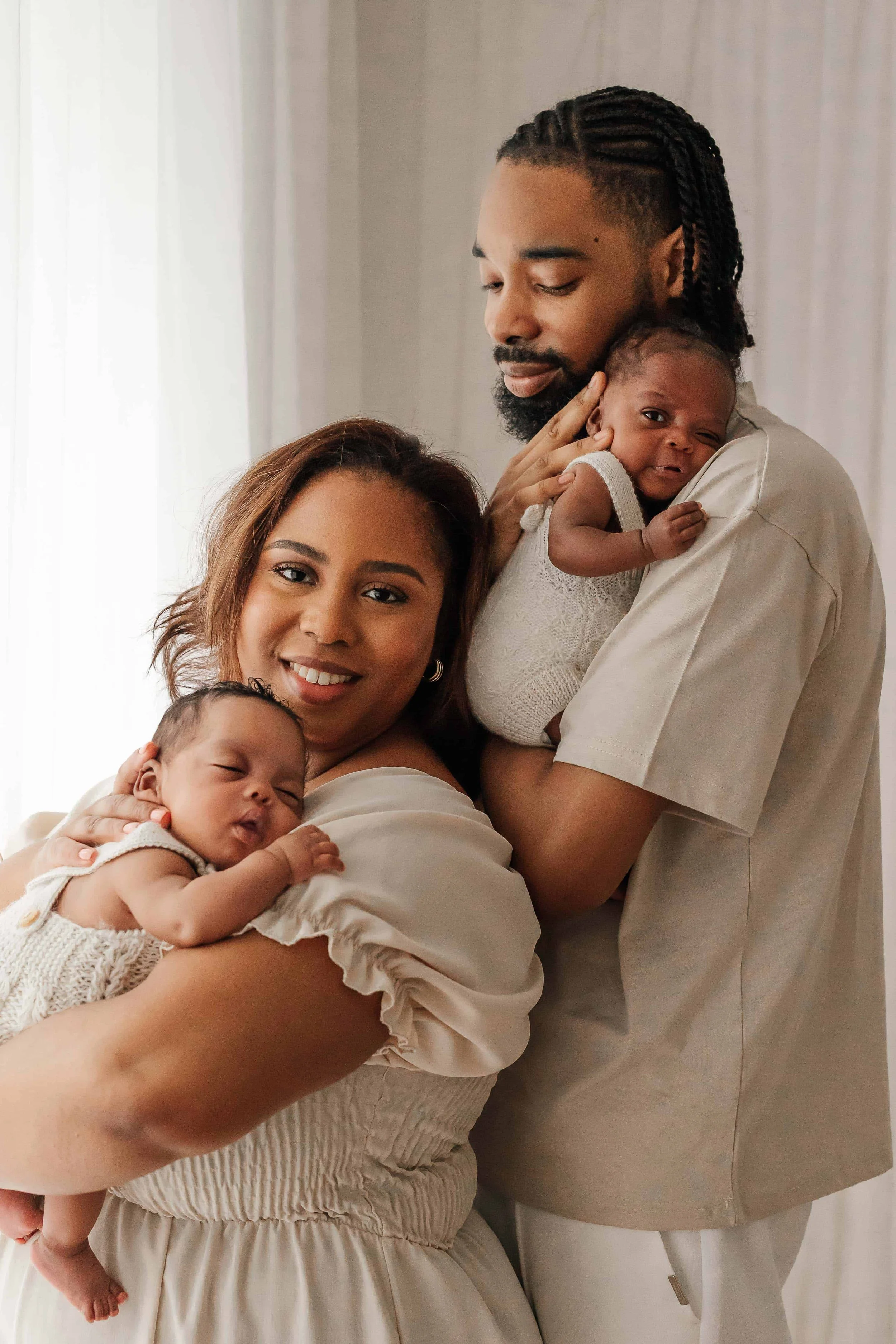 mum and dad holding their twins newborn in their arms and having a family cuddle