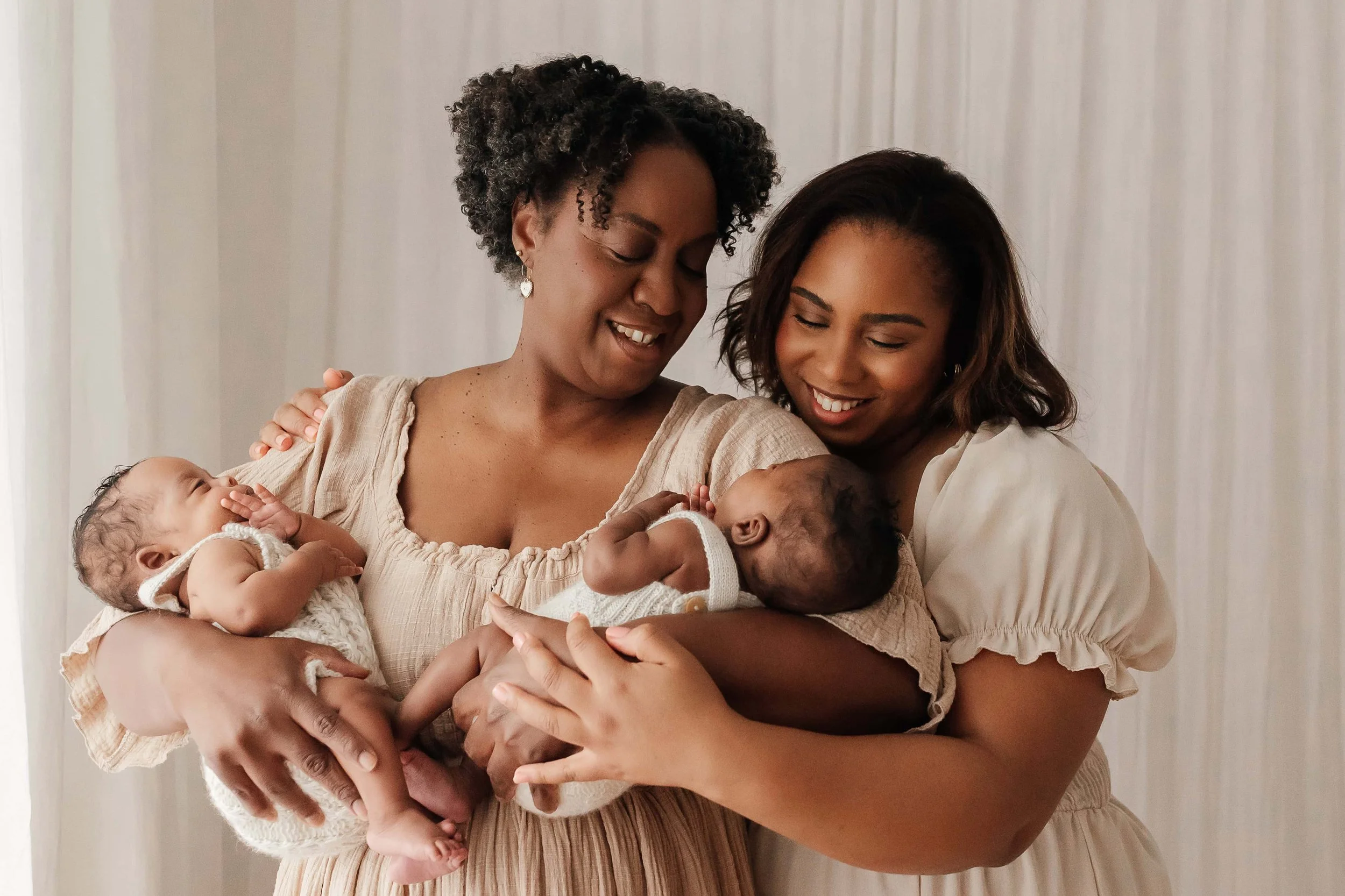grand-mother and daughter holding twin newborns in their arms and smiling