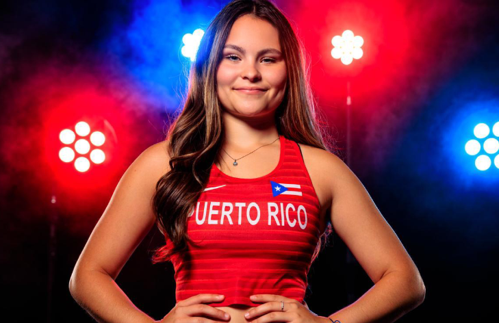 Woman in a red Puerto Rico National Team track uniform with red and blue lights in the background. 