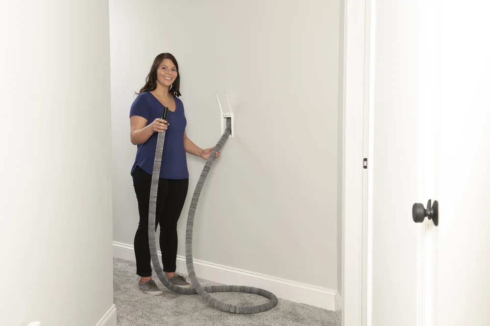 Retractable central vacuum hose being pulled from the wall
