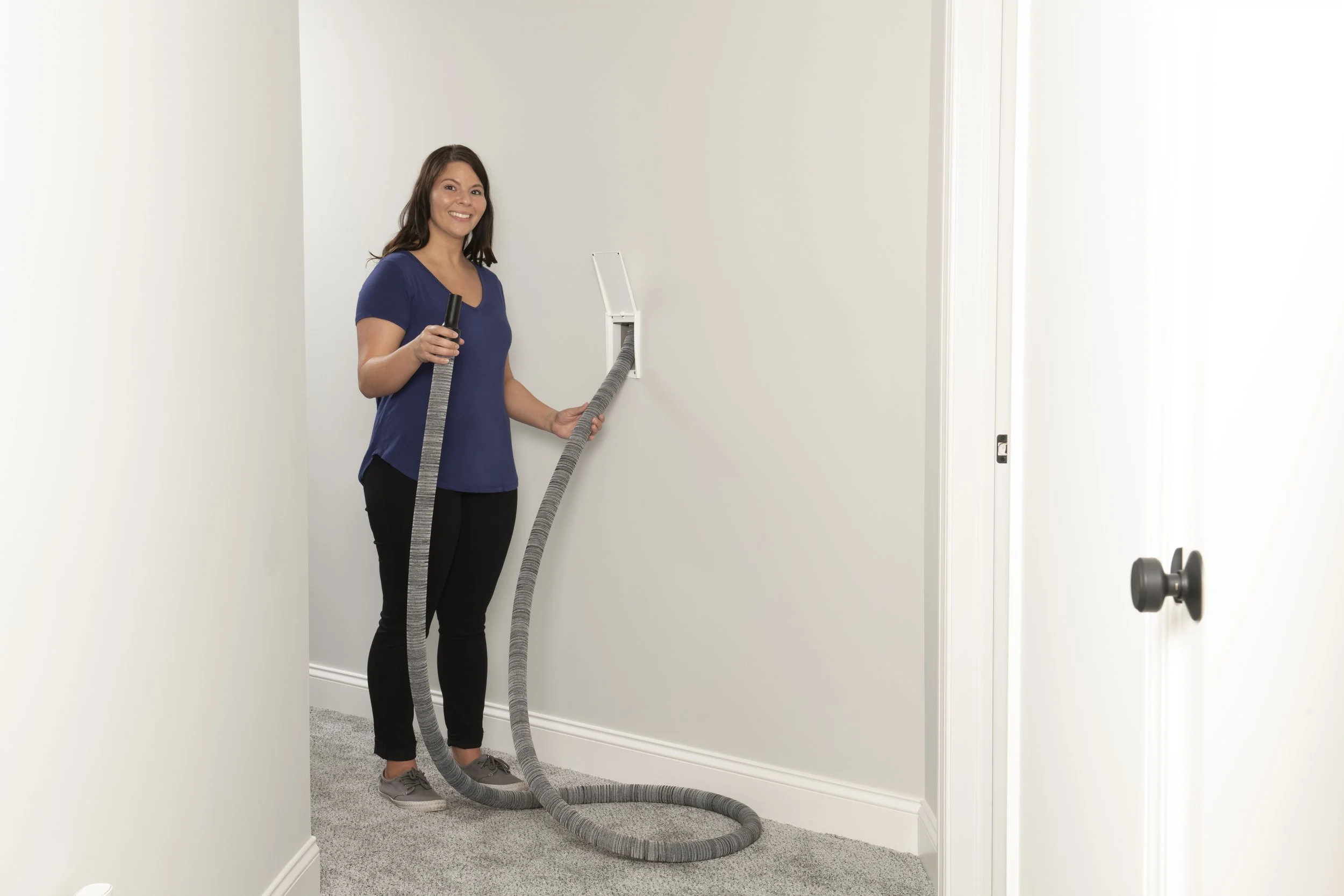 Retractable central vacuum hose being pulled from wall