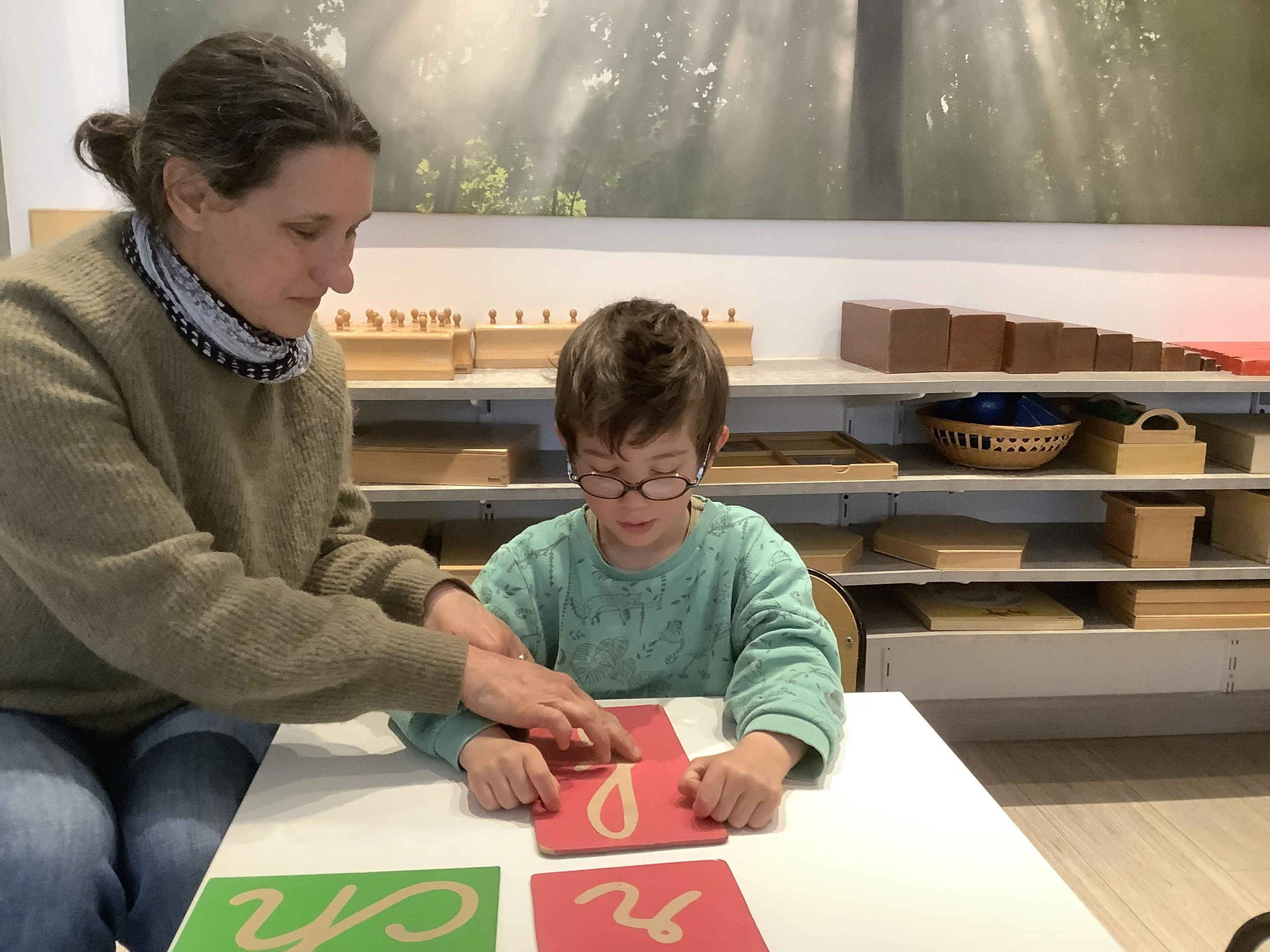 Éducateur Montessori accompagnant des enfants dans une classe bilingue avec du matériel pédagogique favorisant l’autonomie.