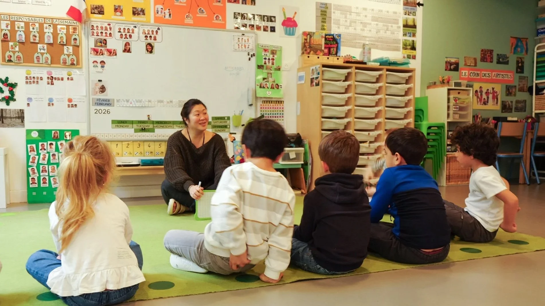 Enseignante Montessori qui anime une activité de langage devant une classe d’enfants en école maternelle bilingue à Paris.
