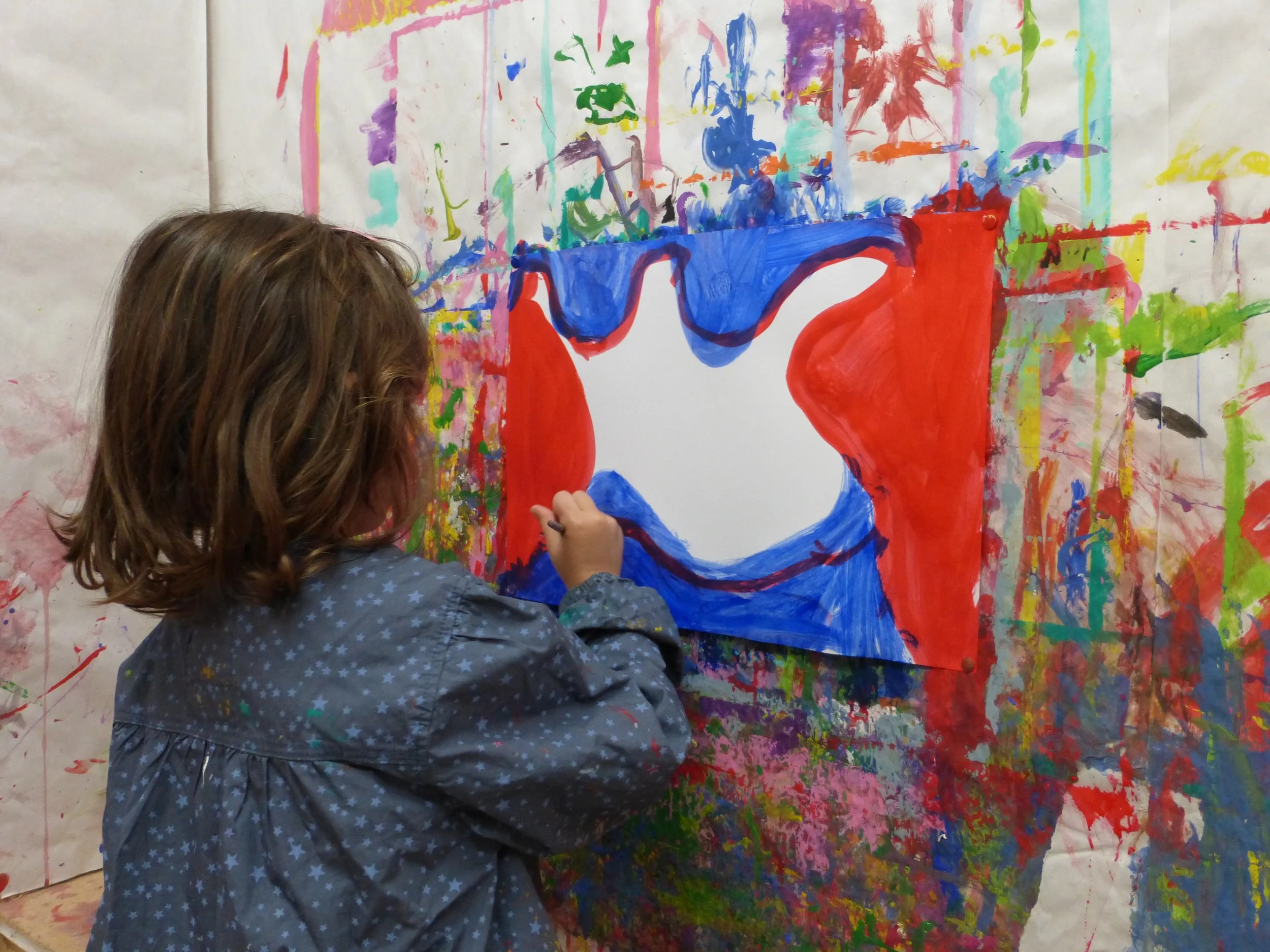 Enfants travaillant de manière autonome dans une classe Montessori bilingue avec du matériel pédagogique adapté à leur âge et surveillés par des éducateurs.
